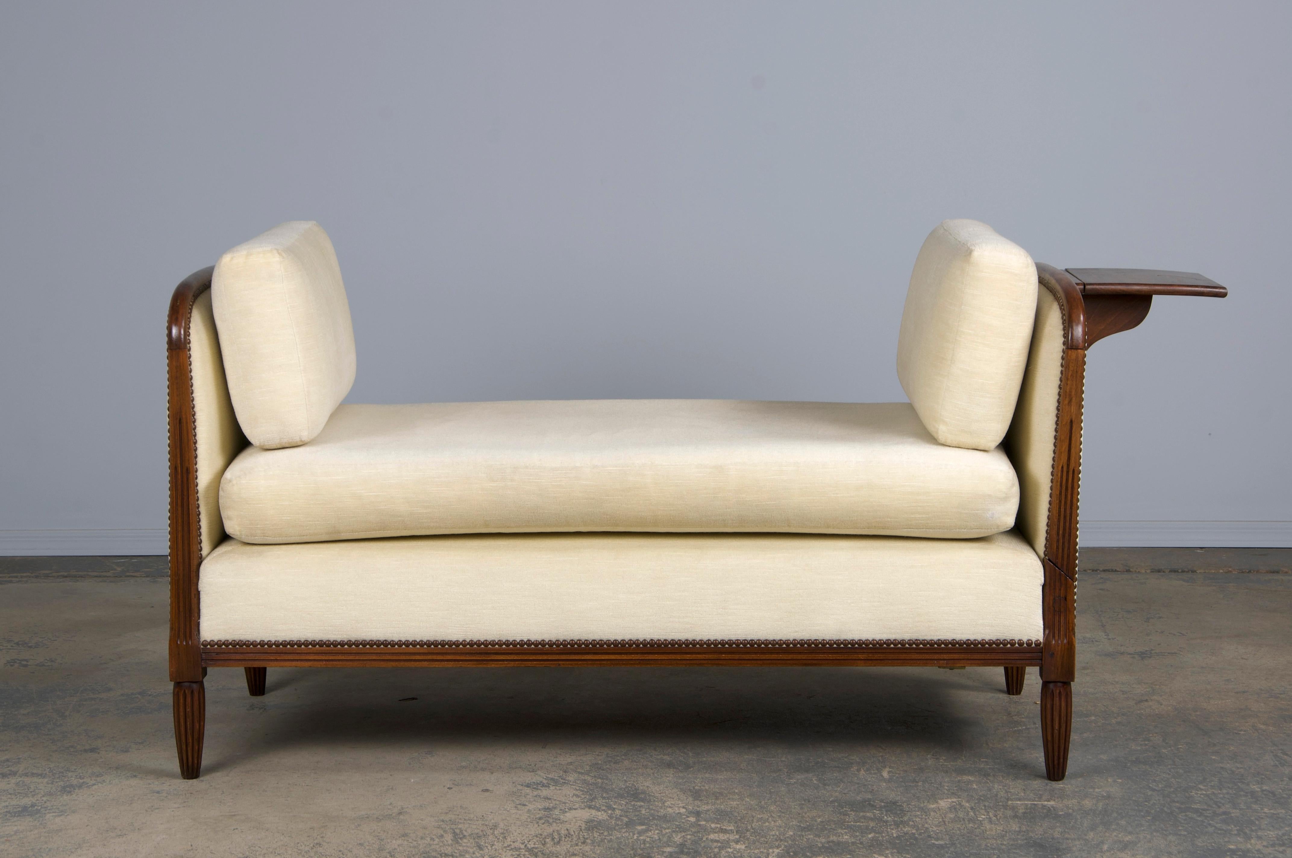 A stylish 1930s French Art Deco loveseat or daybed, sourced from Provence, France. Expertly handcrafted from solid maple wood, it boasts a naturally aged warm patina with rich brown hues and visible wood grains. Upholstered in luxurious cream