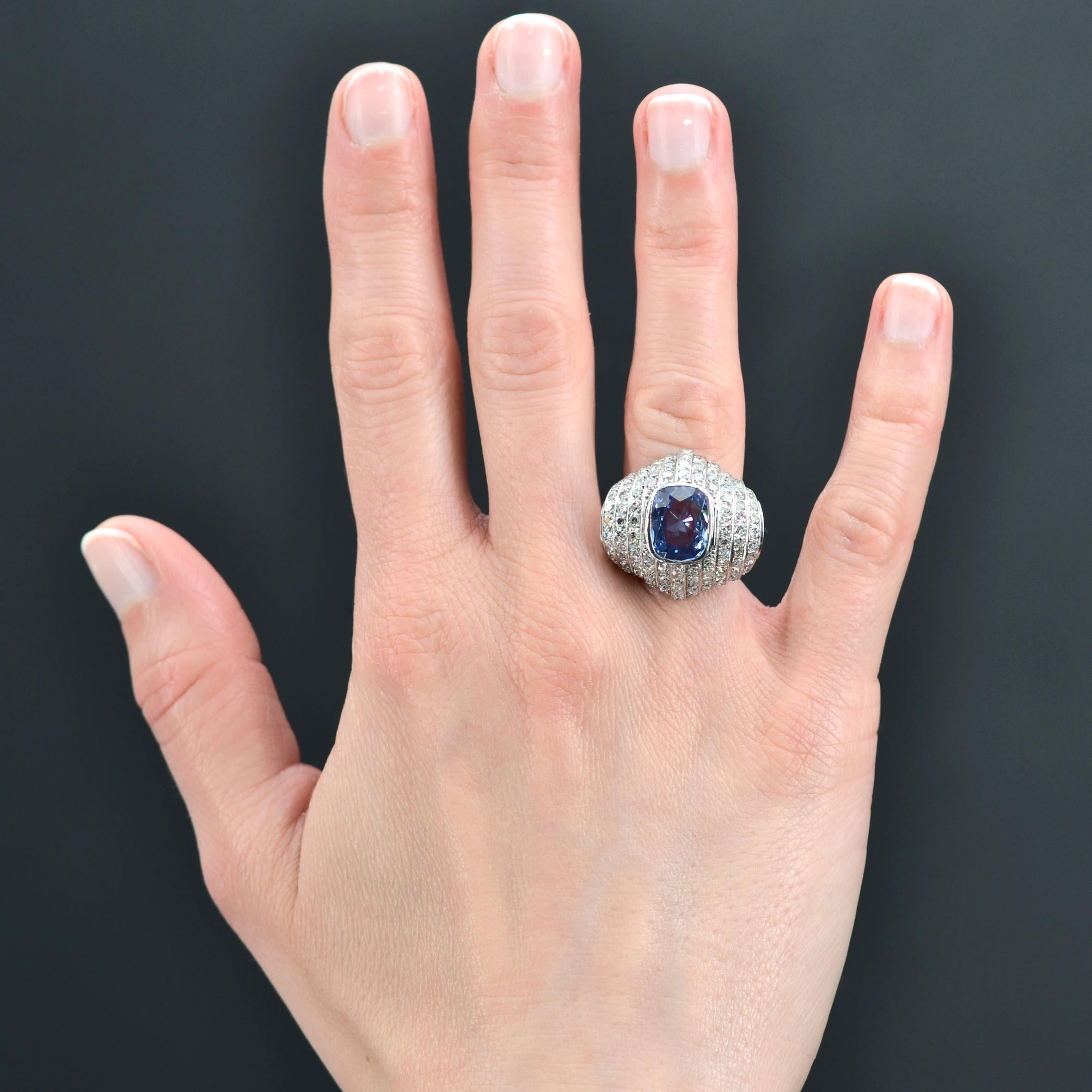 Ring in platinum, dog head hallmark.
Sublime and imposing Art Deco ring, it is set with a natural and certified cushion-cut sapphire on its domed top. The setting is made of falling stepped motifs set with 8/8 and antique- cut diamonds.
Weight of