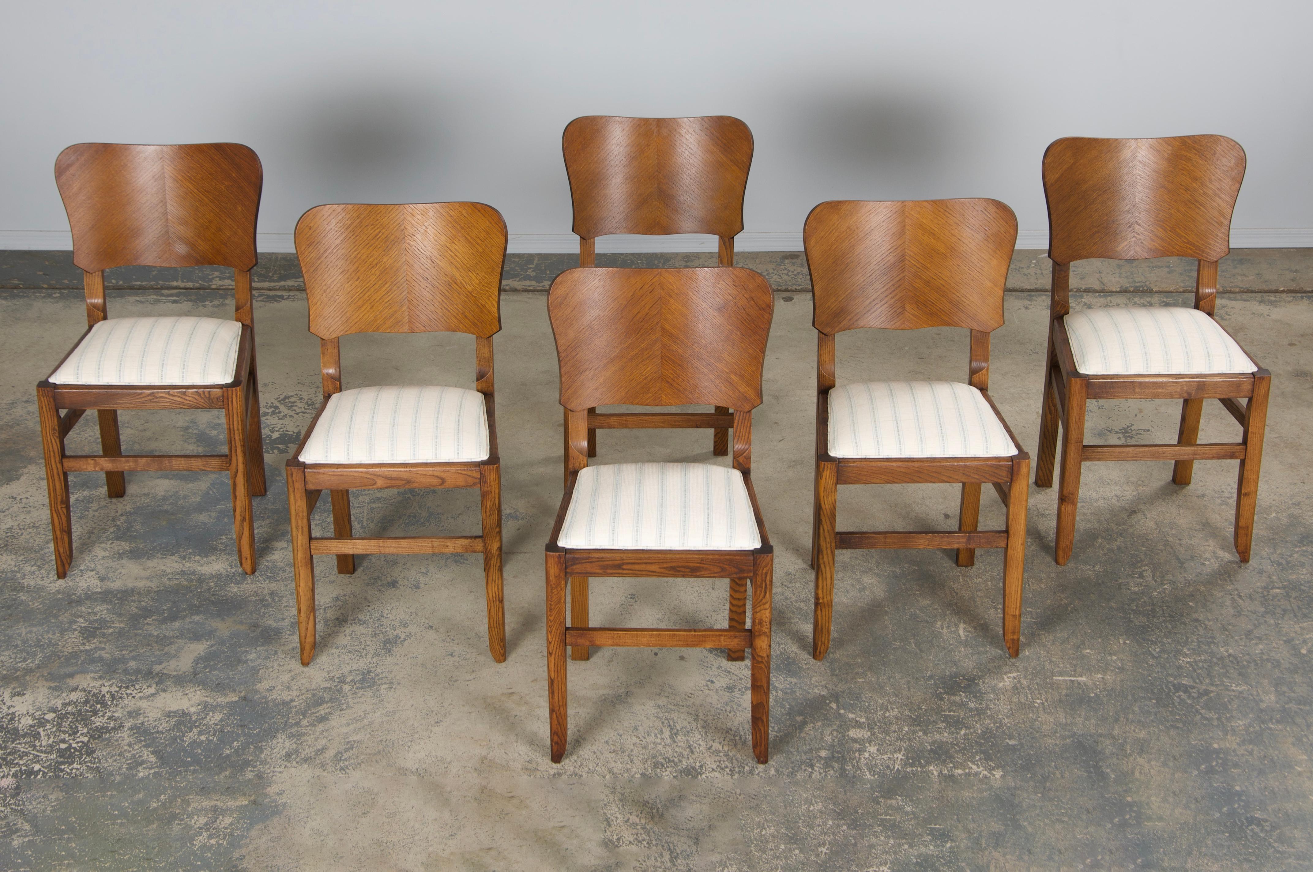 Uno squisito set restaurato di sei sedie da pranzo francesi Art Déco degli anni '30, provenienti dalla Provenza. Realizzata a mano in rovere massiccio, ogni sedia presenta uno schienale quadrato graziosamente curvo con angoli arrotondati, rivestito