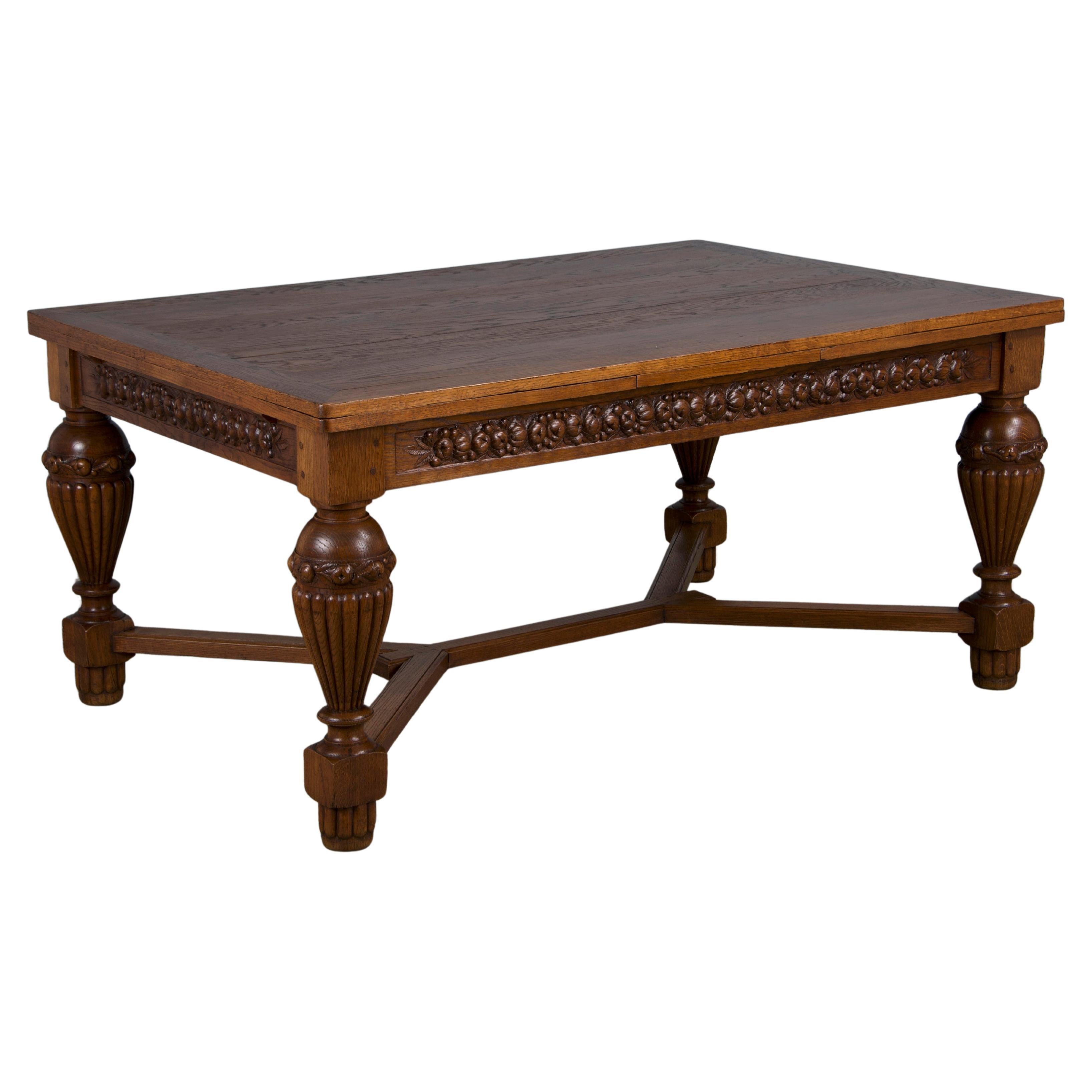 Preciosa mesa de comedor Art Decó francesa de los años 30, hecha a mano en Provenza, Francia, con madera maciza de roble. Esta exquisita pieza presenta intrincados detalles tallados a mano y luce un tablero rectangular con dos extensiones extraíbles