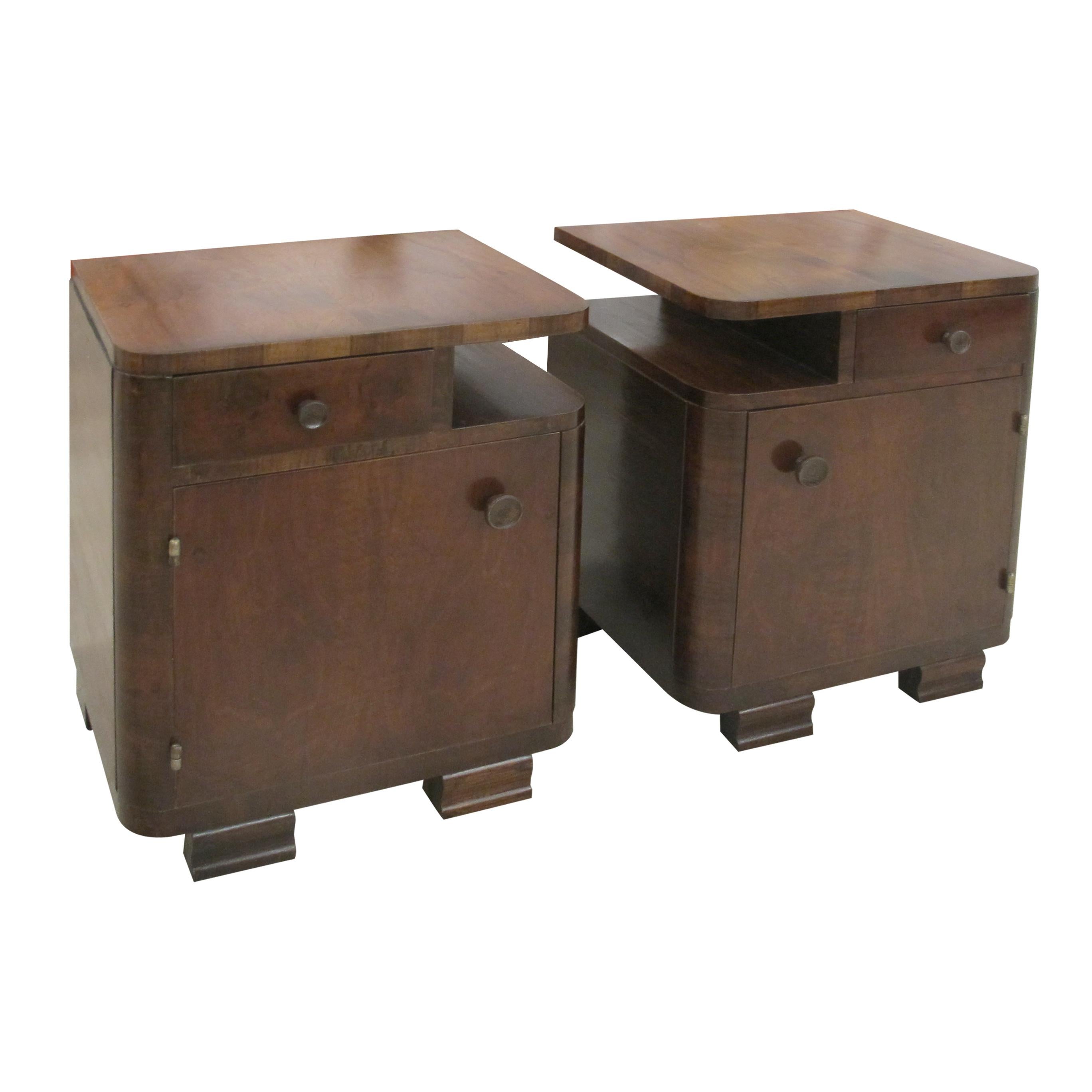 Coppia di comodini francesi Art Déco rifiniti in impiallacciatura di noce. Ogni pezzo è dotato di un cassetto singolo sotto il piano a gradini e di uno spazioso scomparto inferiore per riporre gli oggetti. Il design comprende bordi arrotondati,
