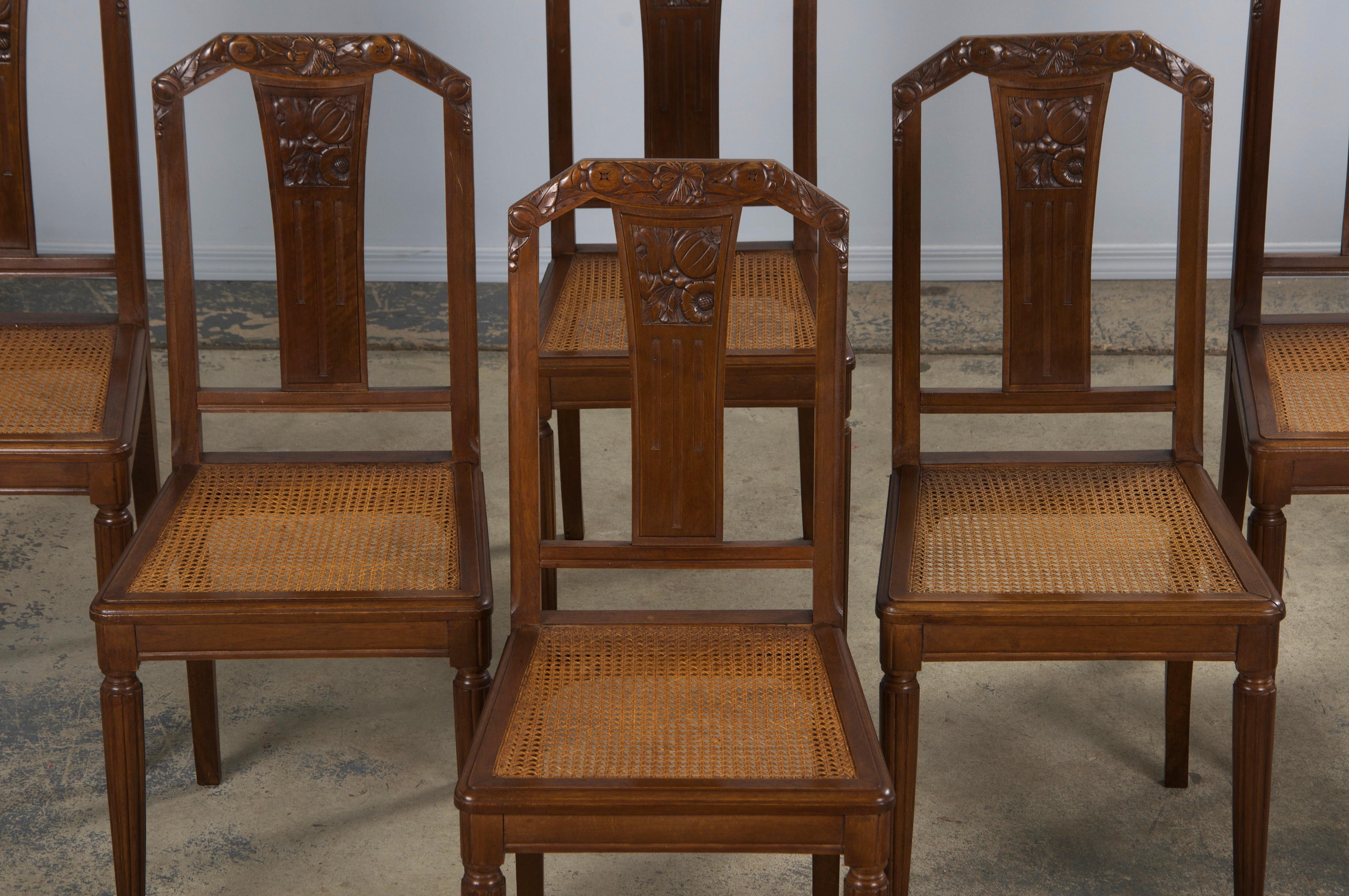 Un tradizionale set di otto sedie da pranzo Art Deco francesi degli anni '30, provenienti dalla Provenza, in Francia. Realizzate a mano in noce massiccio, queste sedie presentano una struttura dello schienale elegantemente intagliata e decorata con