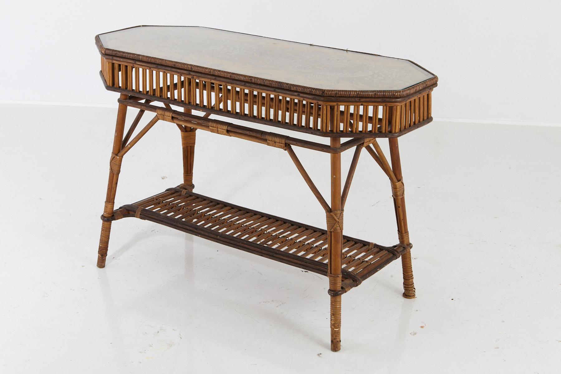 1930s French octagonal bamboo and wicker console table with glass top and a second tier.
The table is in good, solid and stable condition, the is a small piece of wicker missing on the apron
and the fabric under the glass is a bit frayed on the