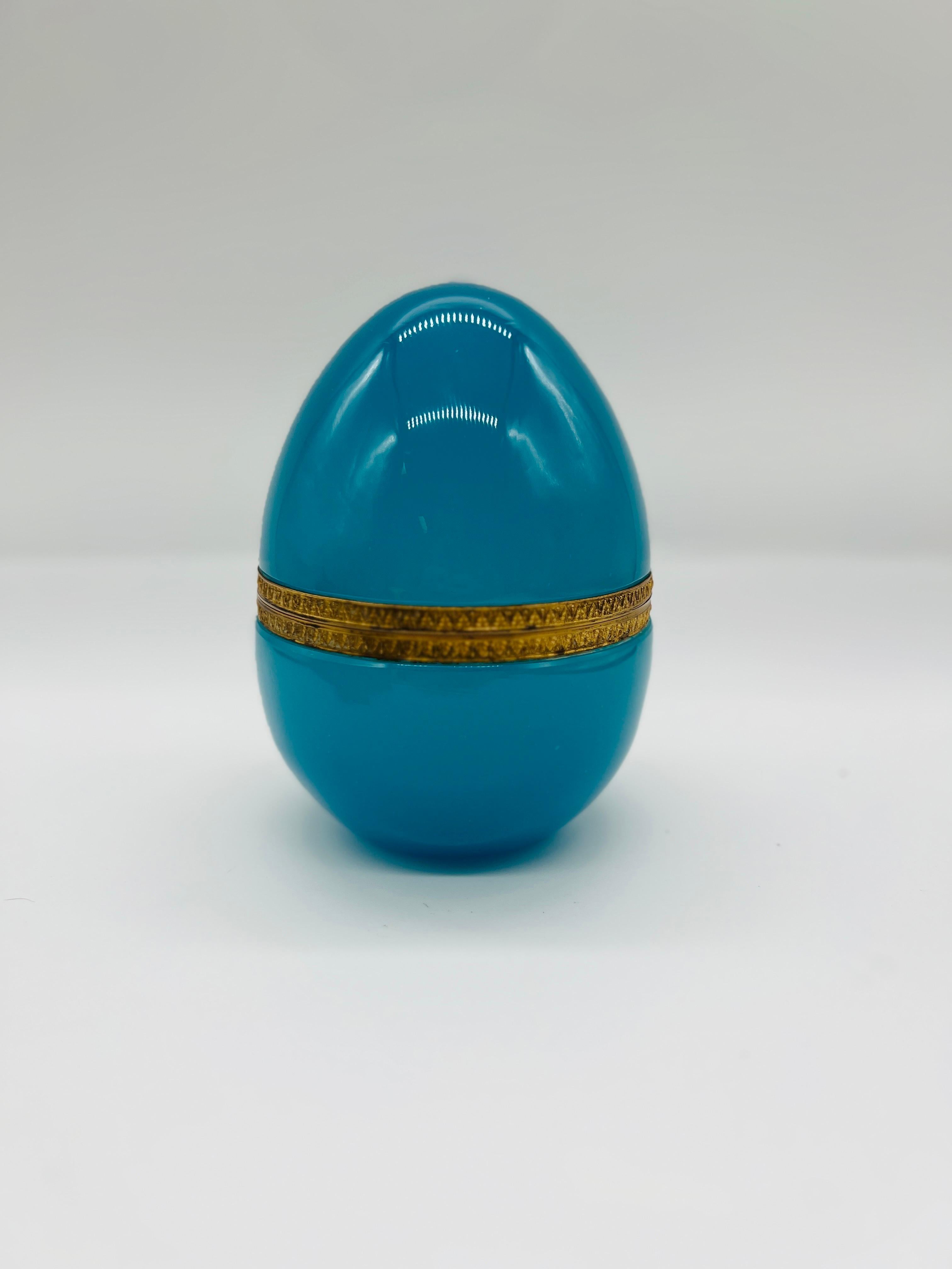 French, 1930's. 
An antique French blue opaline glass egg trinket box. This larger sized egg has a hinged design with foliate engravings to the ormolu band. Unmarked. 