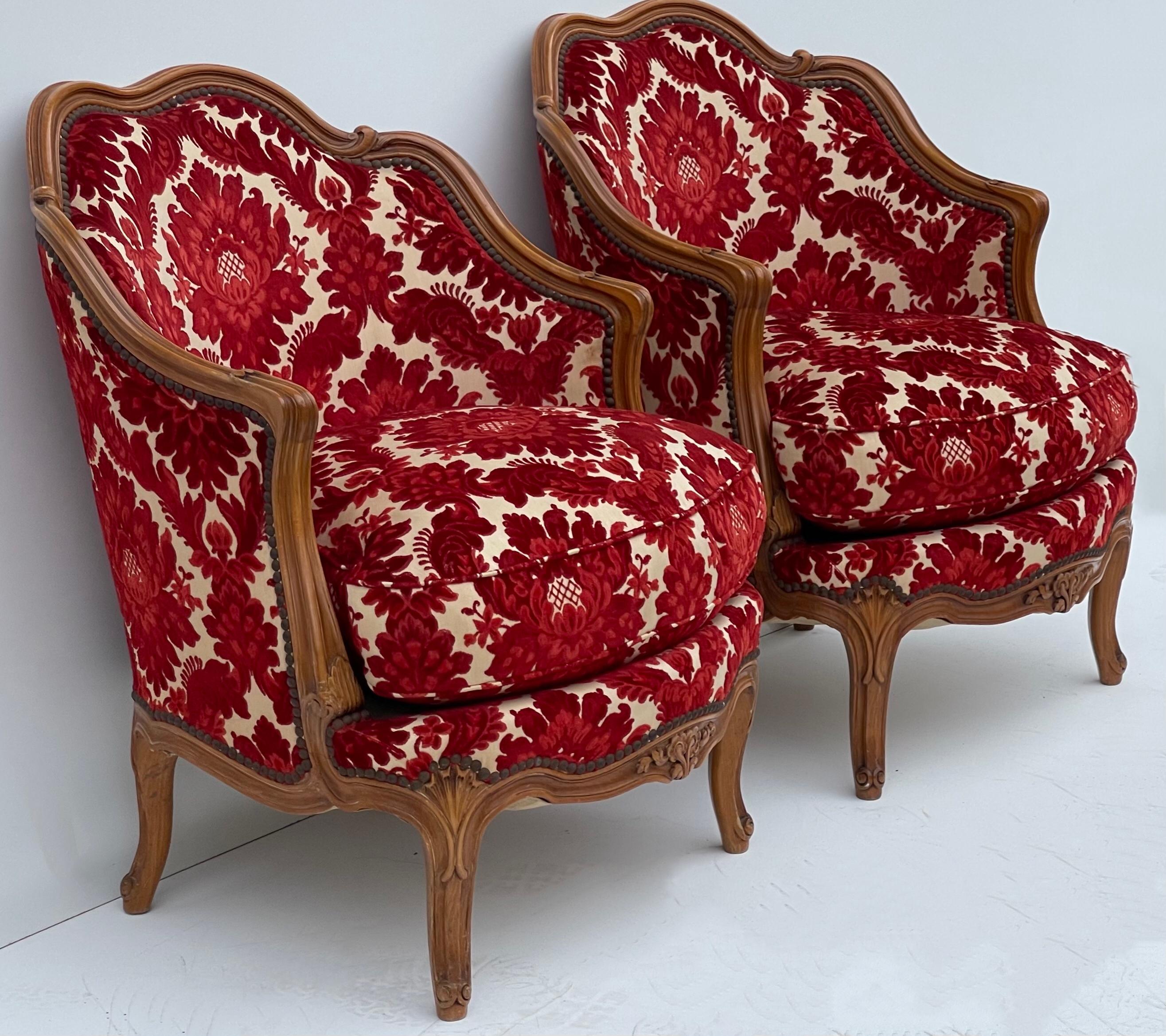This is a wonderful pair of French carved fruitwood chairs in a vintage red cut velvet damask. Note the carving along the base and tops of the legs. The cushion is a thick down.