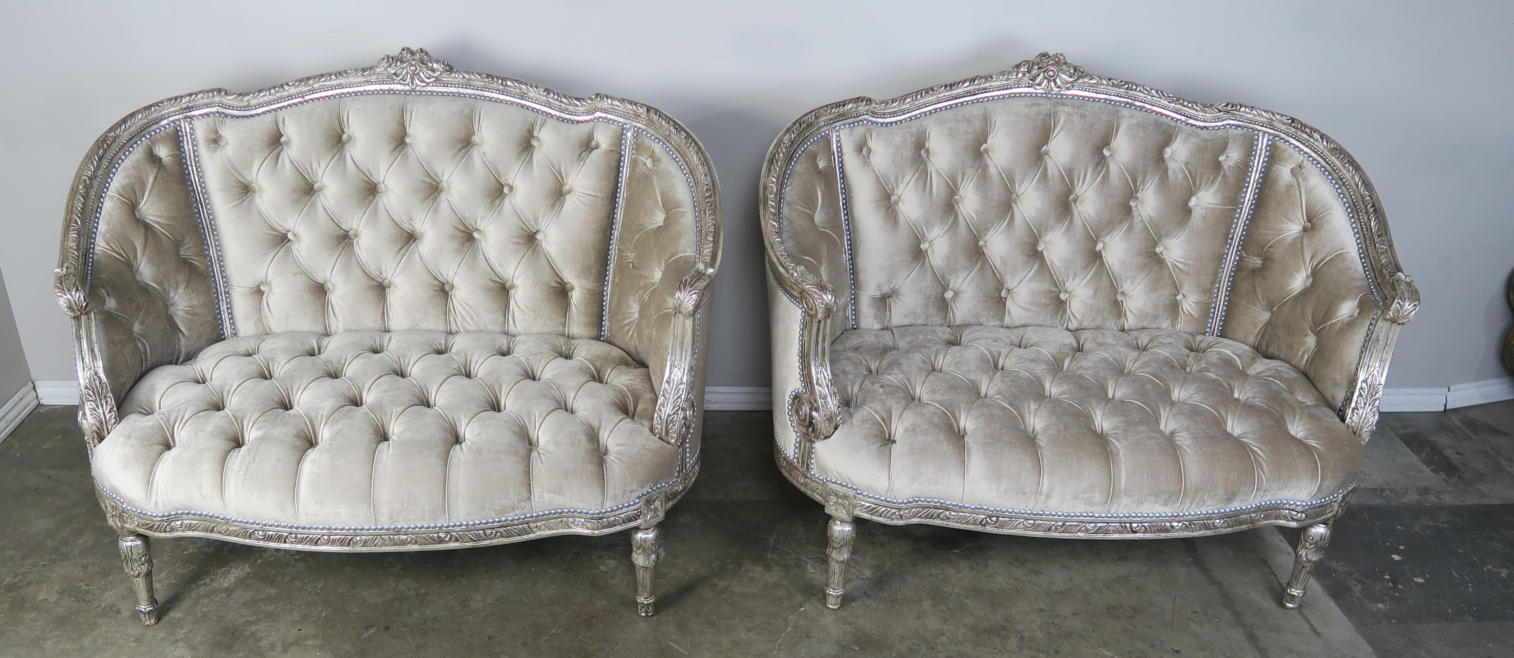 Pair of French carved wood silver gilt settees stand on four straight legs and were newly upholstered in a platinum colored tufted velvet with silver nailhead trim detail.
Seat height 16