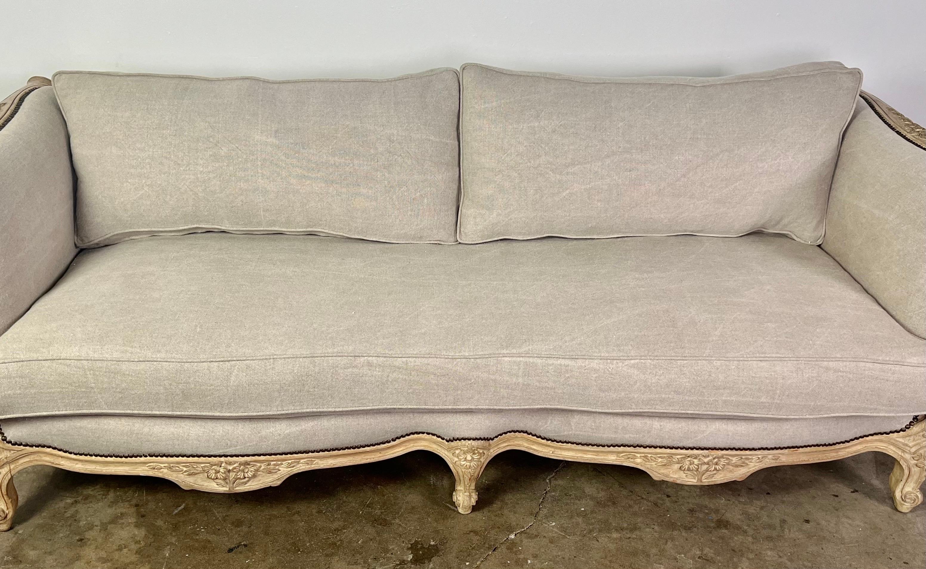 1930s French carved Louis XV style carved sofa upholstered in Belgium linen. There is a loose dacron filled seat cushion and two soft decron back cushions.