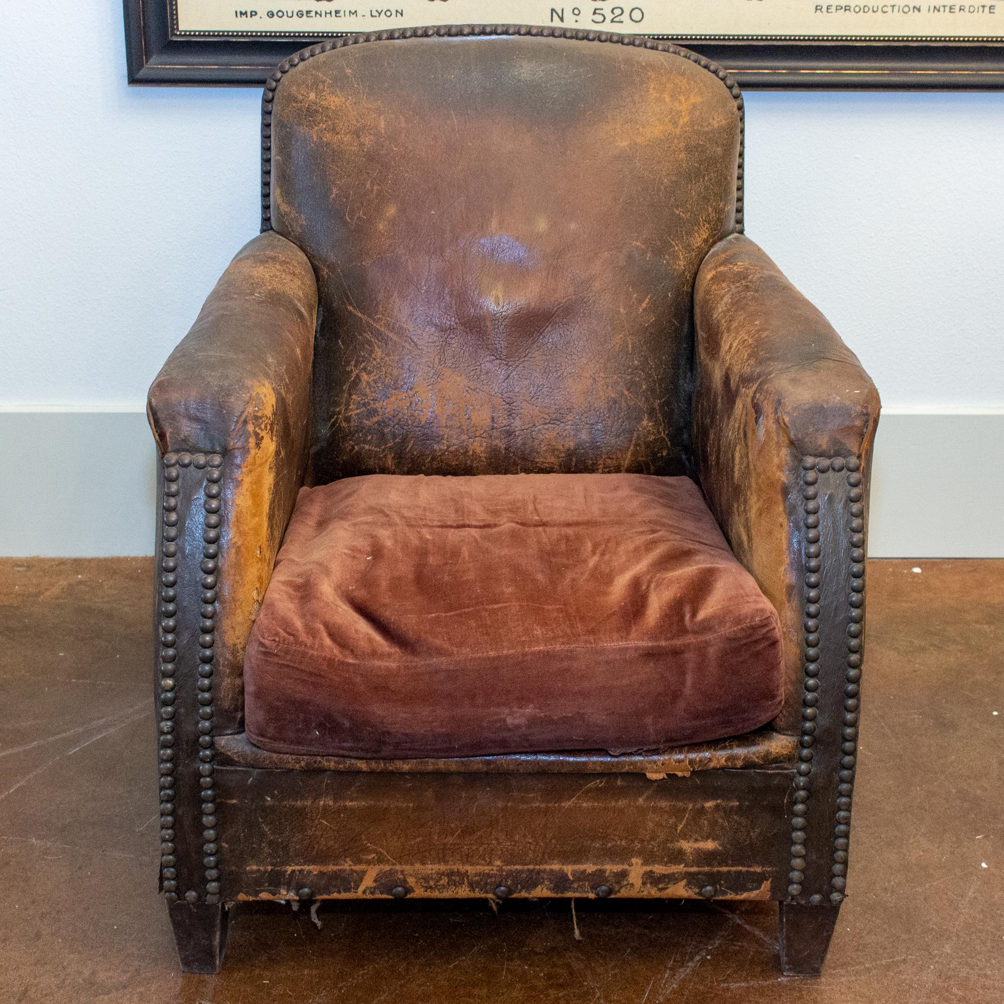 This beautifully weathered and patinated French leather armchair features classic brass nailhead details and a matching velvet seat cushion. This armchair is comfortable, cozy and exactly as soft as it looks. Structurally sound and very supportive,