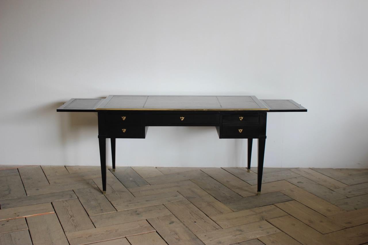 A circa 1930s French bureau plat, later ebonies in the Louis XVI taste, with brushing slides, that will work well in most settings.
Measurements when fully open: 208cm wide x 60.5cm high (knee height).
