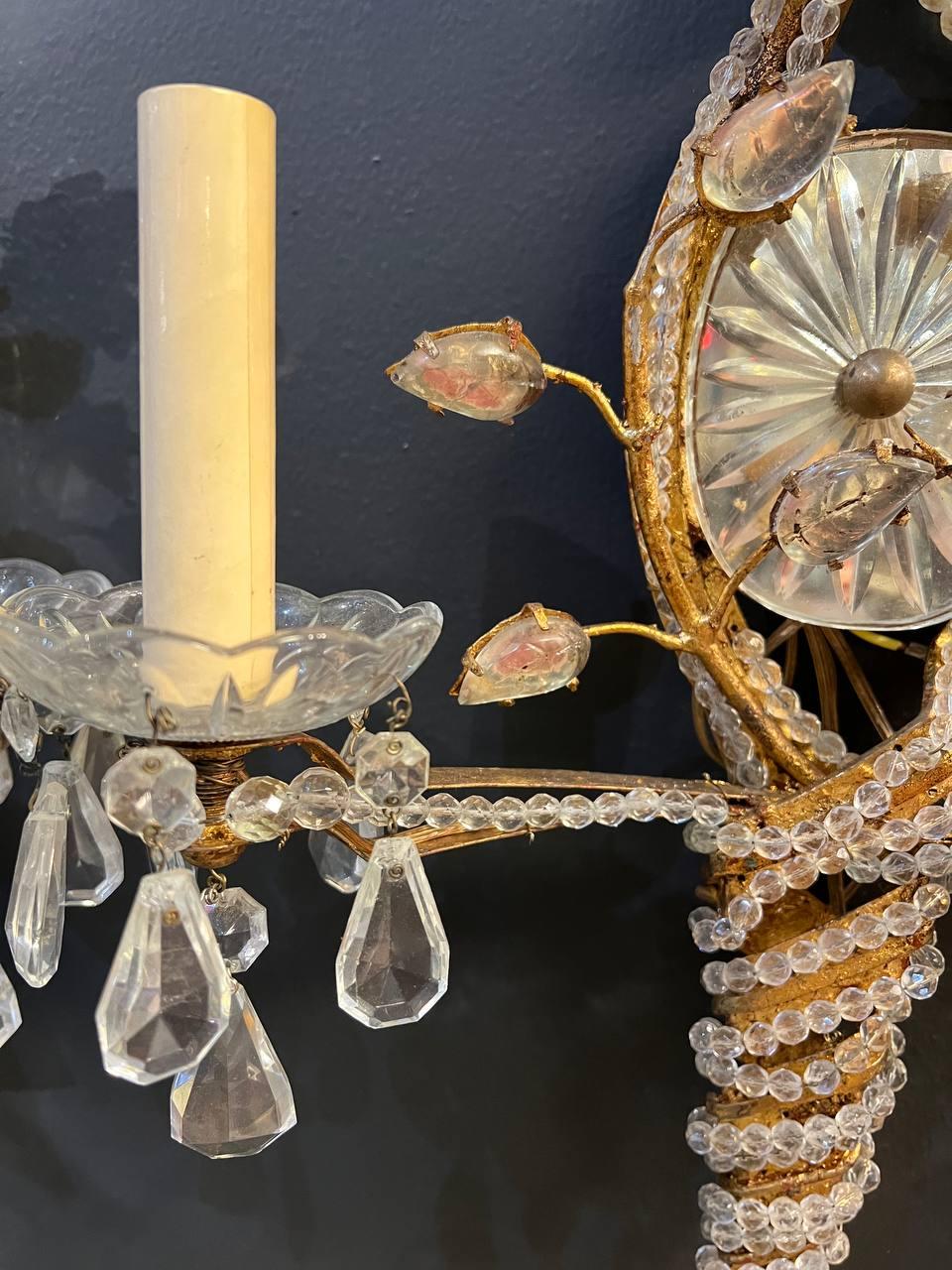 A pair of 1930’s French twisted gilt metal sconces with beaded crystals and mirrored backplate. Available in silver plated finish