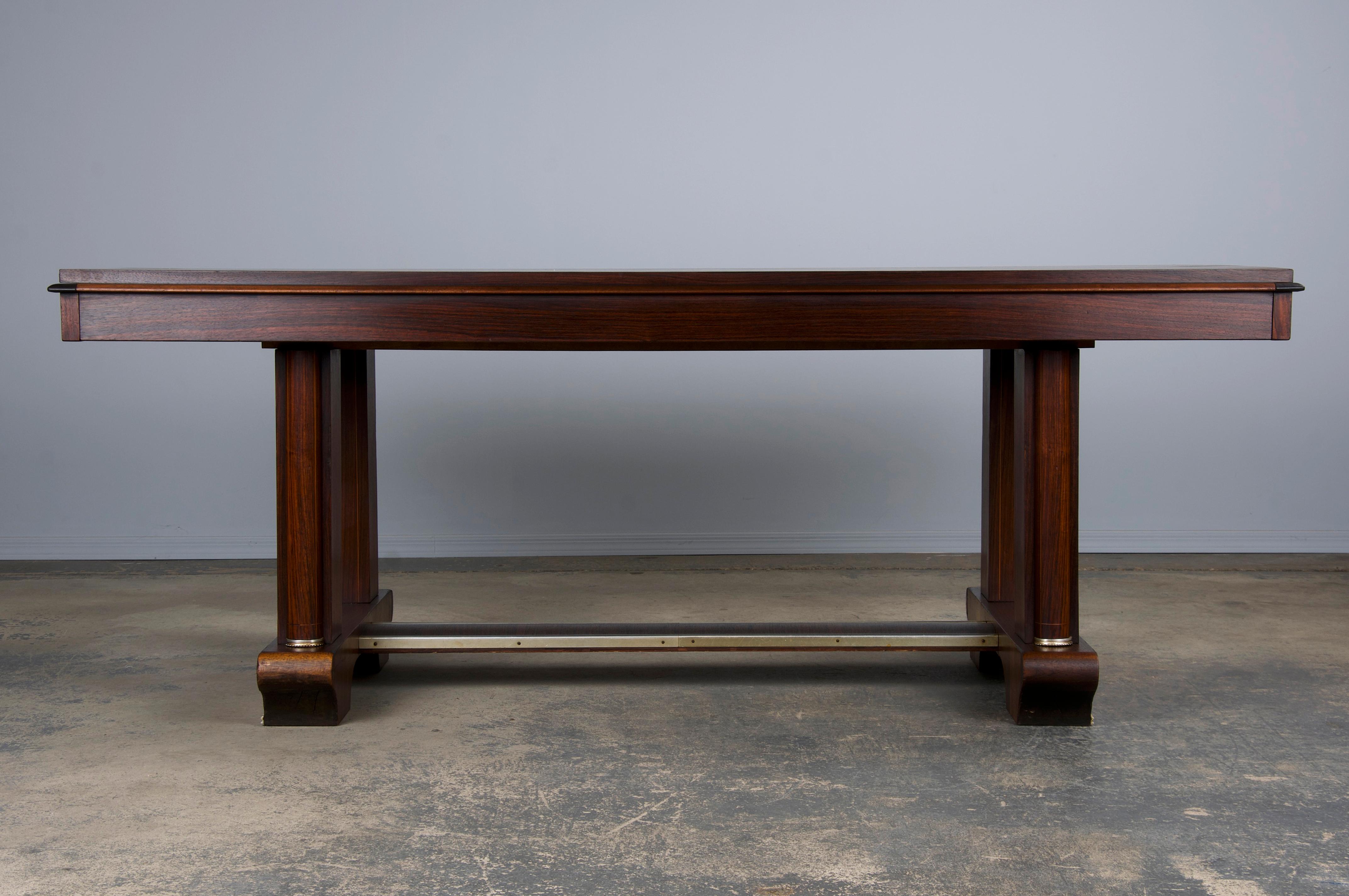 An elegant 1930s French dining table, attributed to Jules Leleu, sourced from Paris, France. Expertly hand-crafted from rosewood, the table showcases a stunning parquetry top adorned with delicate inlay work. The wood has developed a naturally aged