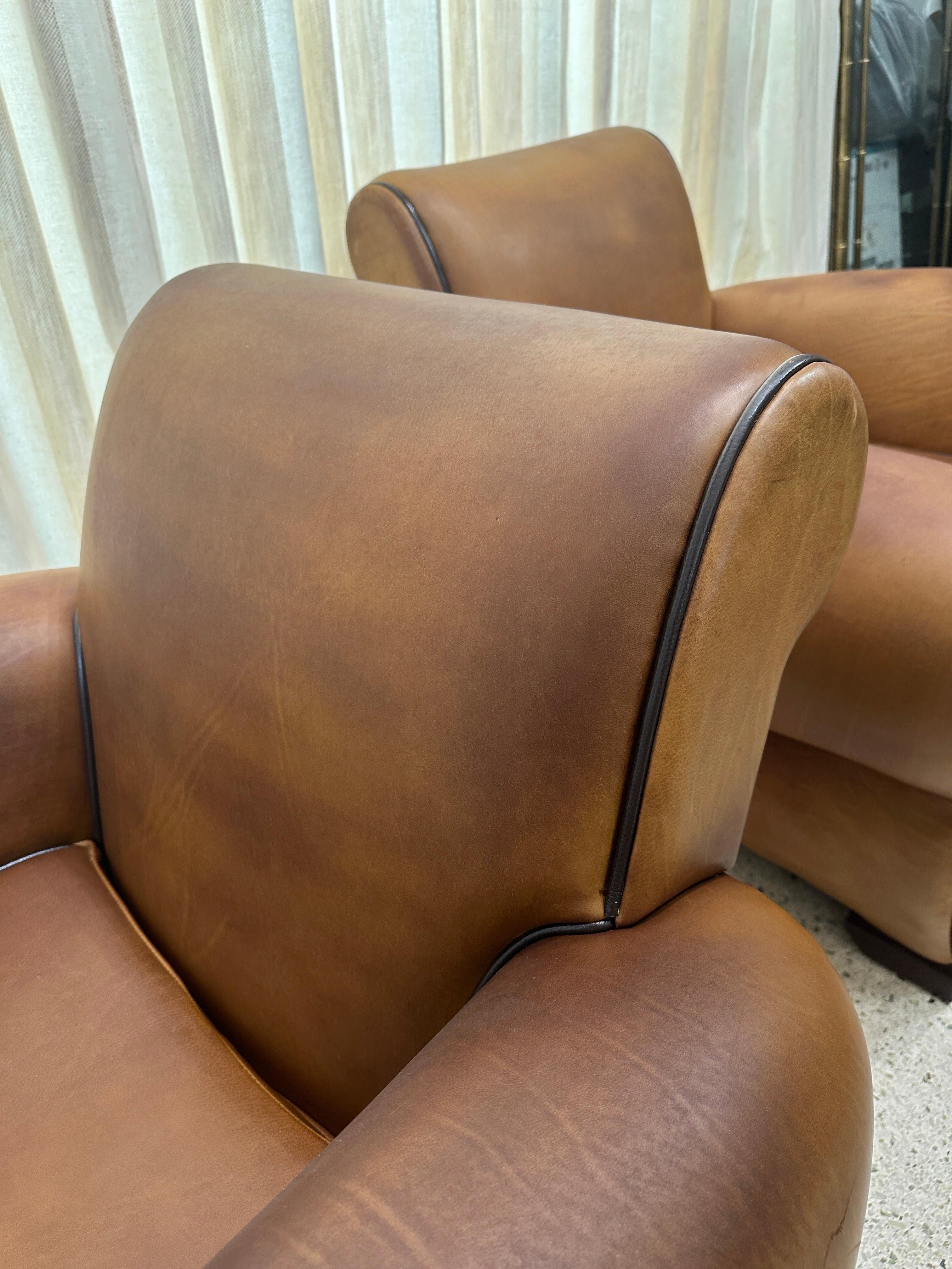 Extremely desirable pair of French leather club chairs in original soft leather in light cognac tone.  Shows dark coloration in some areas from regular use but overall very appropriate for their age.  Classic Art Deco design to arms and deep seating
