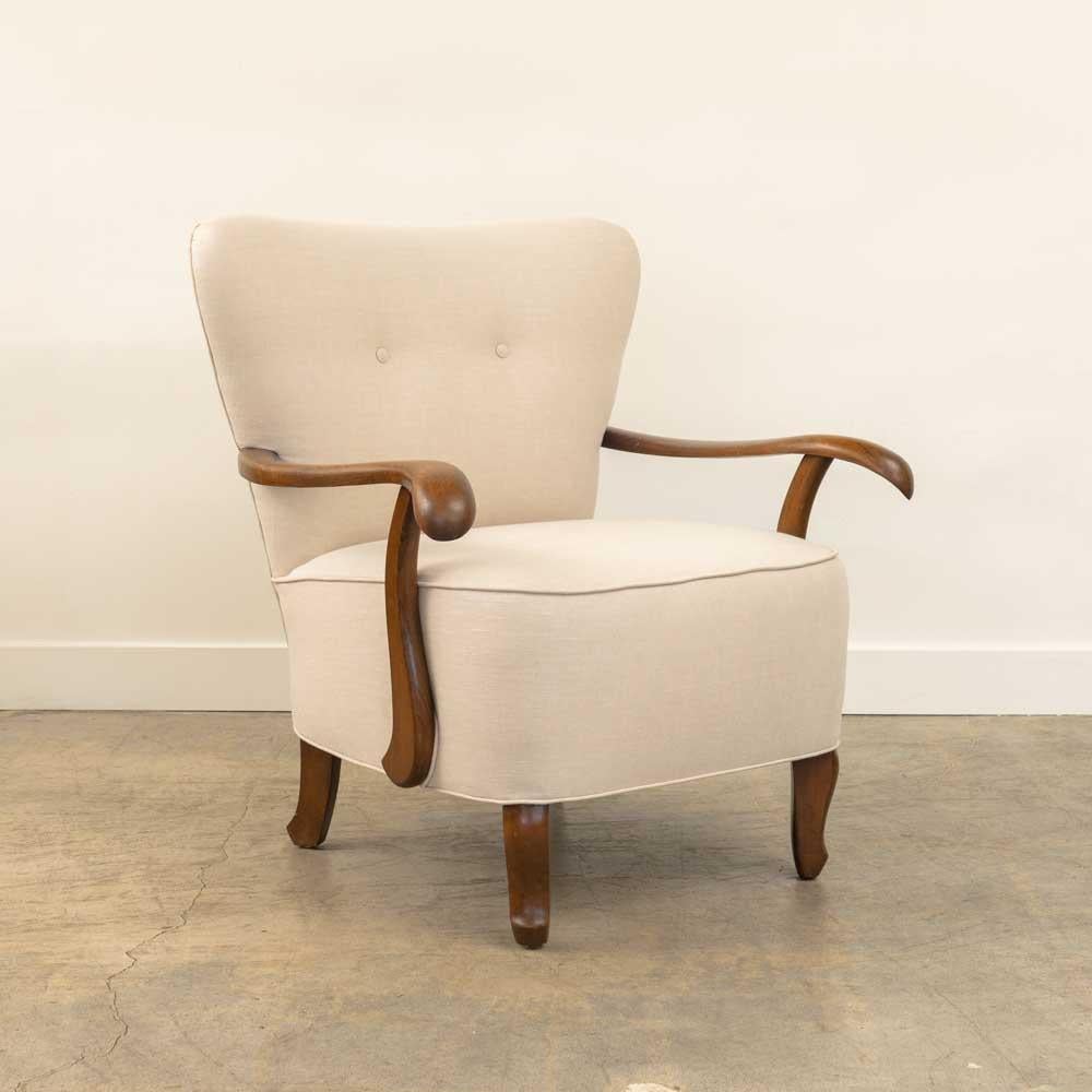 Incredible upholstered armchair from France, 1930's. Newly upholstered in a creamy linen with button detail. Beautifully curved wood arms and wood tapered feet in a medium stain. Stunning and unique vintage chair. 