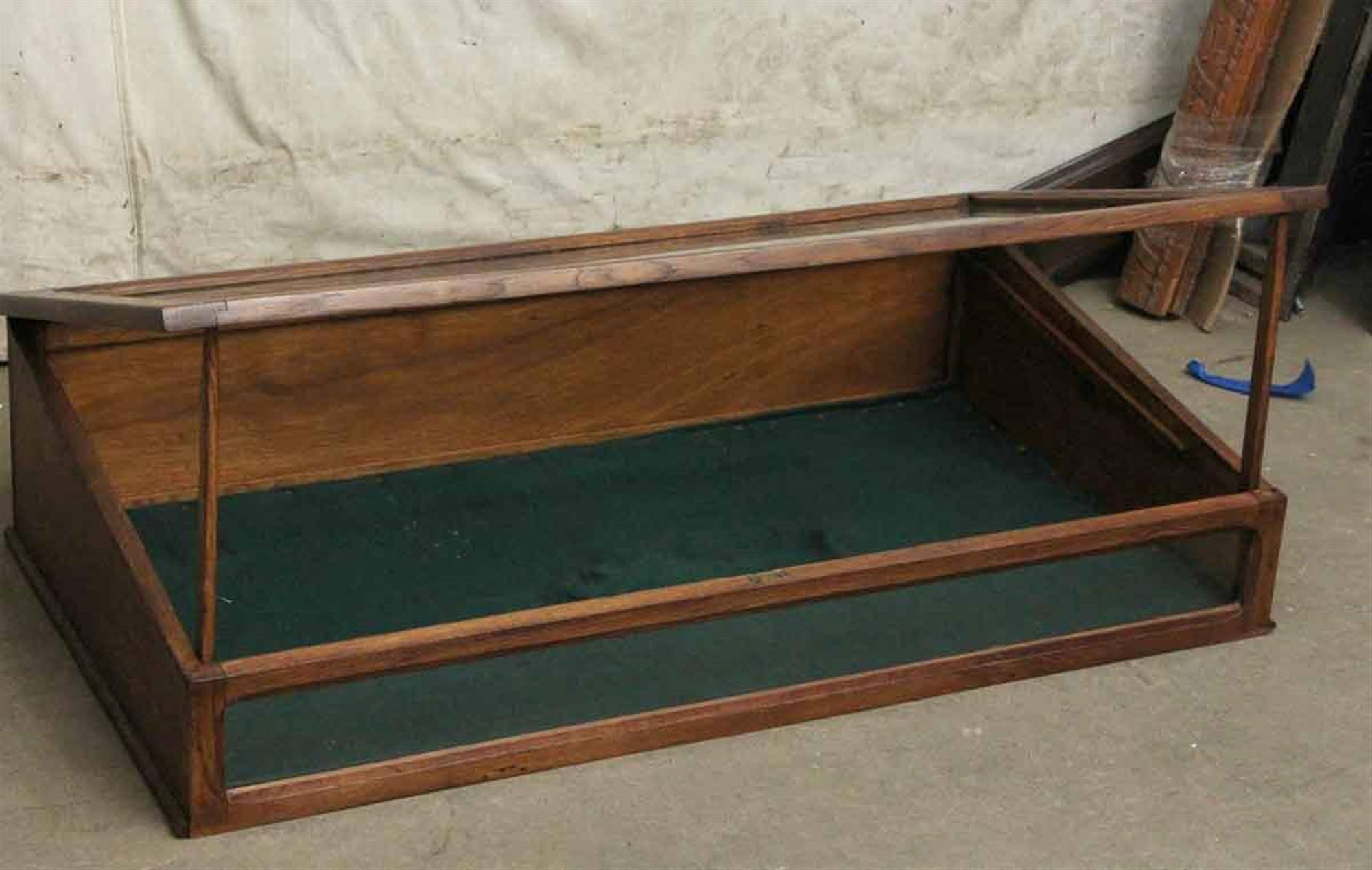 1930s dark wood tone oak display case with a green interior in good condition. This is a great use for jewelry. Two available at time of posting. Priced each. This can be viewed at one of our New York City locations. Please inquire for the exact