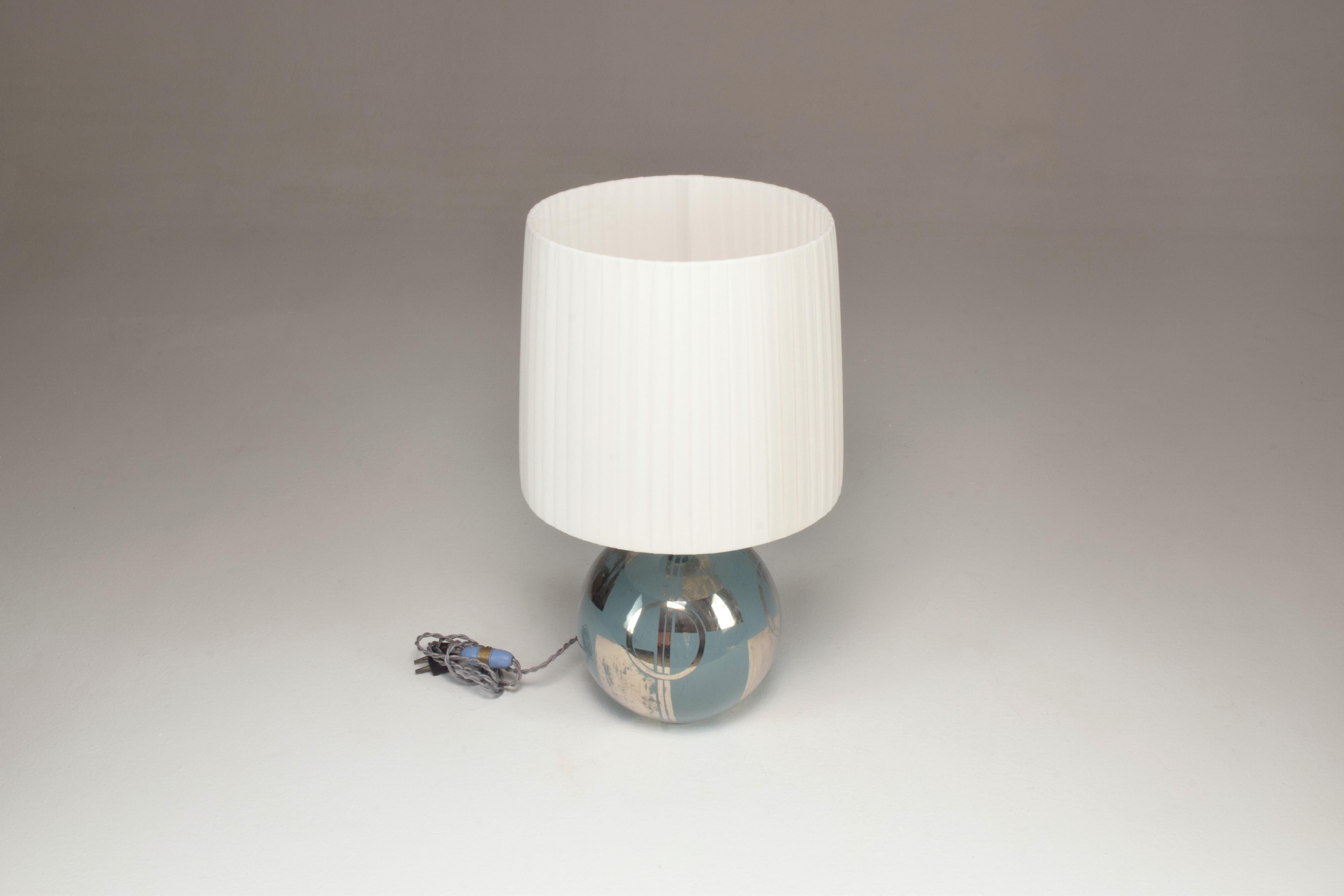 It is a highly original early 20th-century vintage round table lamp that stands out with its handpainted geometric light blue and silver faded lines and squares. 
Restored with a new shade, original switch,
France, Circa 1930's 

We are an
