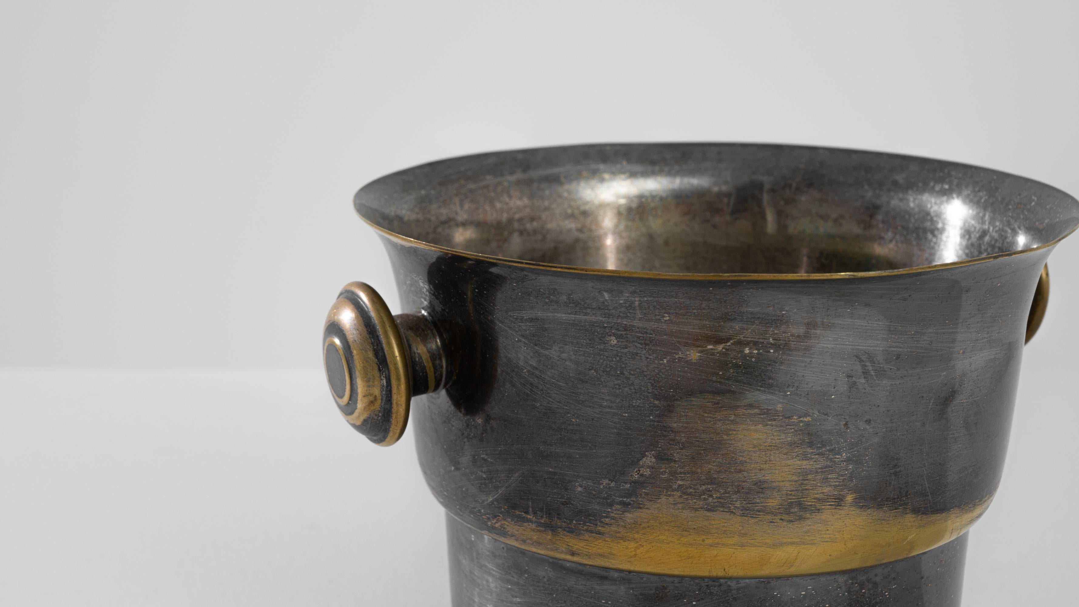 This lidless ice bucket was made in France, circa 1930. A silver plated bucket elegantly patinated to reveal its brass underlayer. The original rounded handles with concentric circles mimic the three parts shape of the bucket, unfolding like a