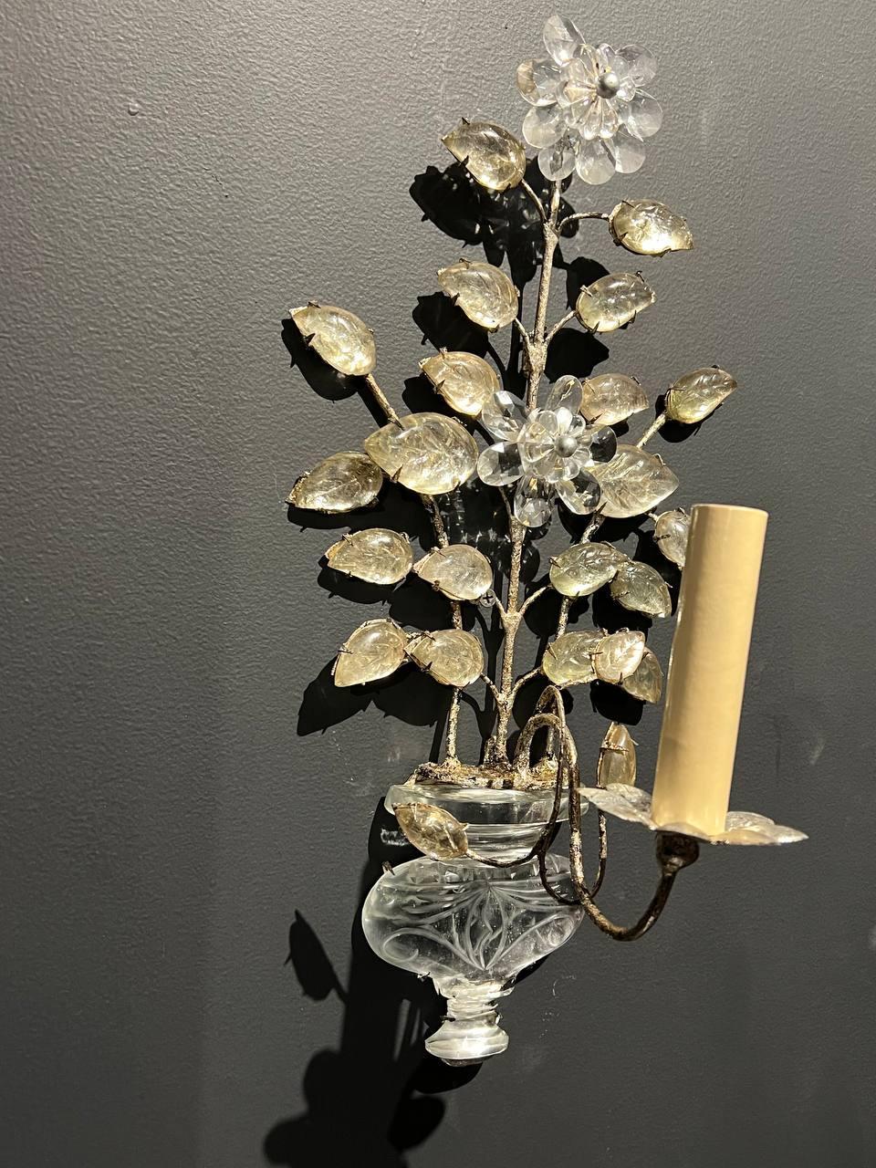 Un par de apliques de una luz de metal plateado con hojas y cuerpo de cristal