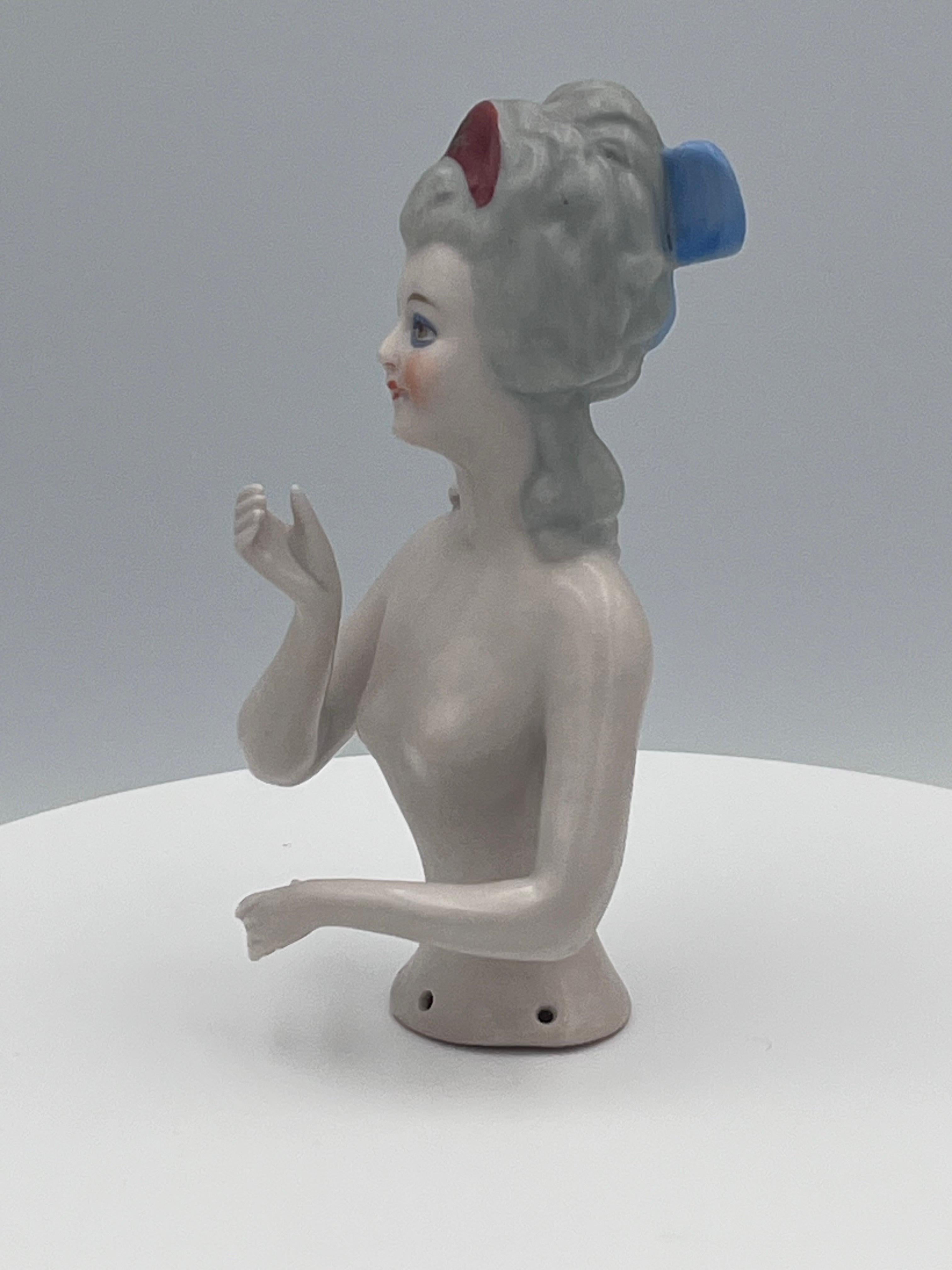 Superbe demi-poupée en porcelaine Art déco allemande des années 1930 avec coiffure rococo

Cette exquise demi-poupée en porcelaine allemande des années 1930 reflète la beauté raffinée et le glamour intemporel de la période Art déco, associés à