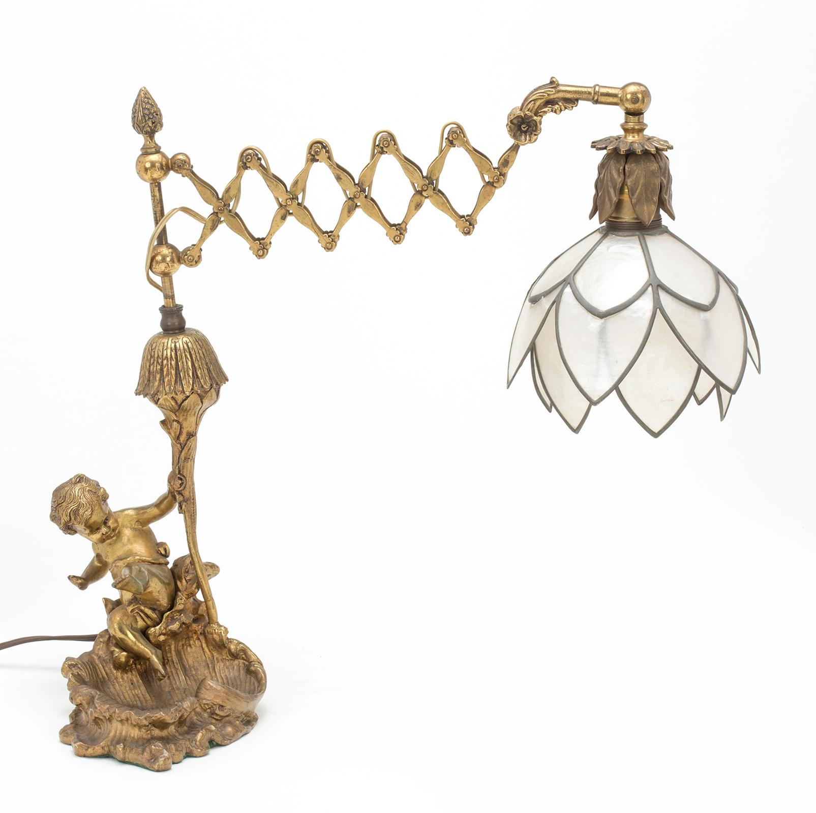 Charming gilt bronze cherub holding up light post that extends and retracts for easy reading. The shade is petals shaped layers of mica shells, giving a soft luminescent light.