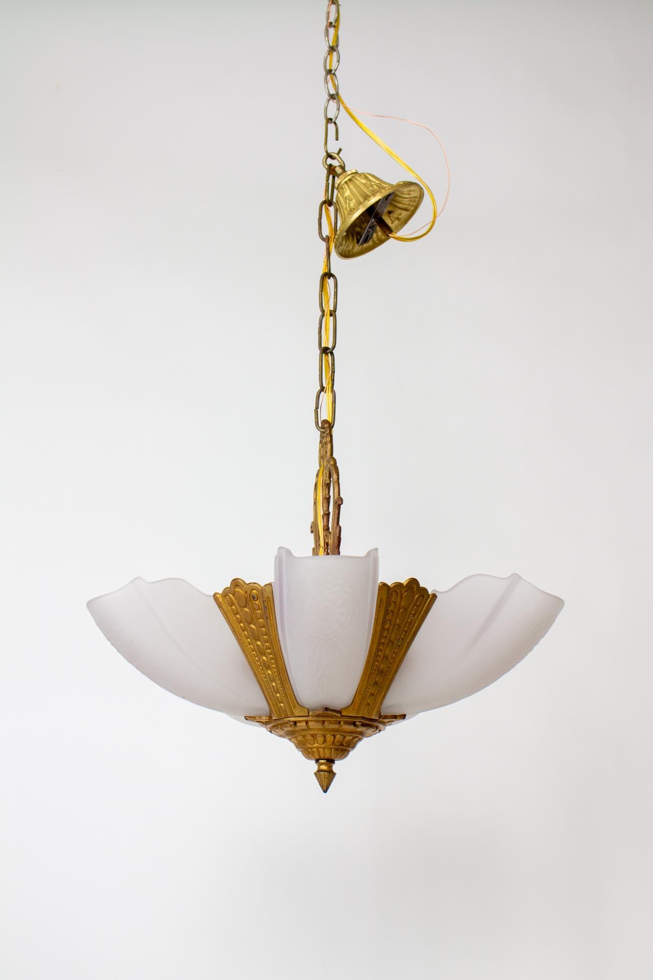 An authentic 1930's Gold Art Deco Slip Shade Chandelier. This chandelier embodies the essence of the Art Deco era, characterized by its sleek lines, geometric shapes, and simple finishes. The cast iron body of this chandelier boasts its original