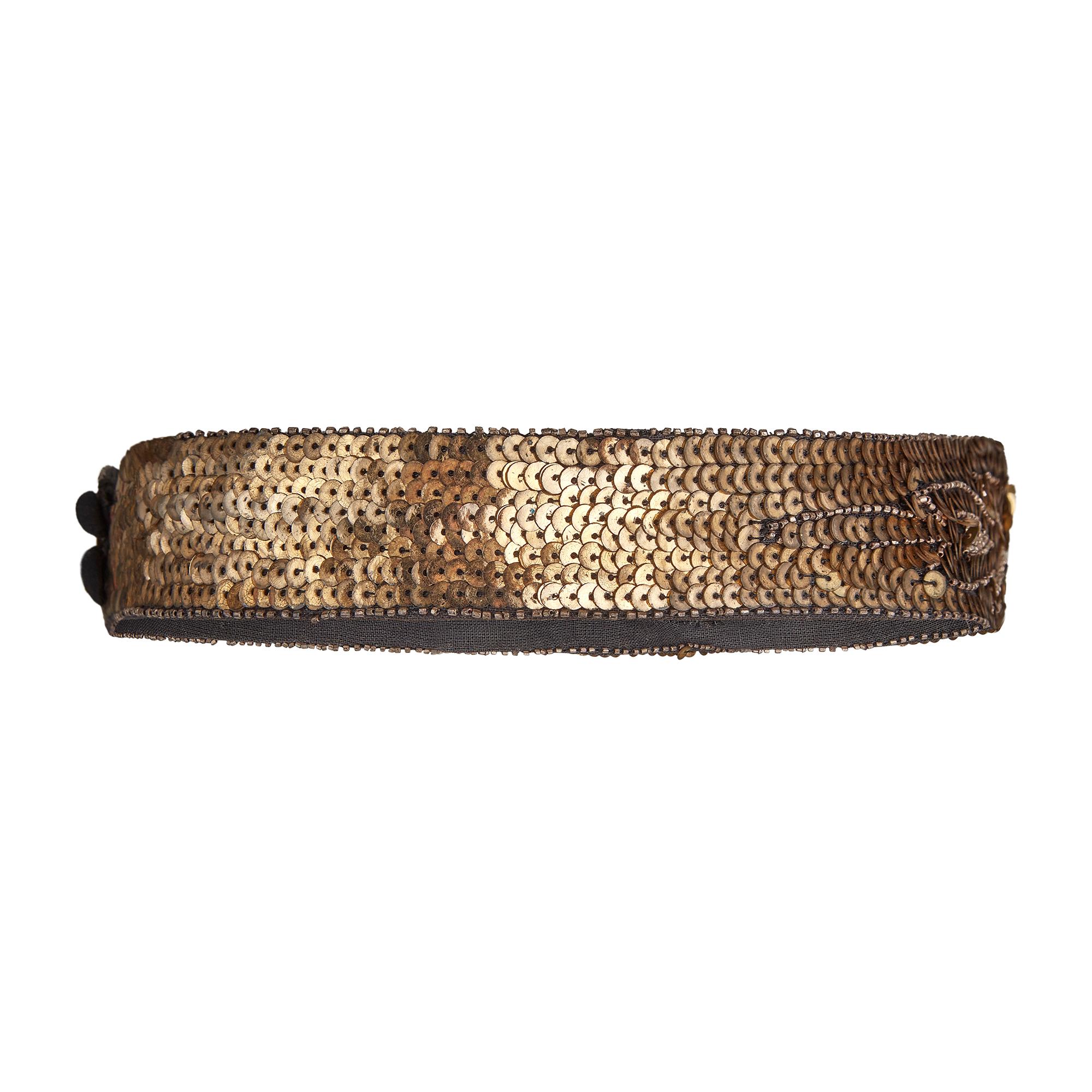 Burnished gold sequins sit upon darkest grey linen cloth on this late 1920s to early 1930s made belt. The wider front of the belt displays sequins arranged in an Art Deco motive with abstract patterns swirling out towards the edges.  Interspersed