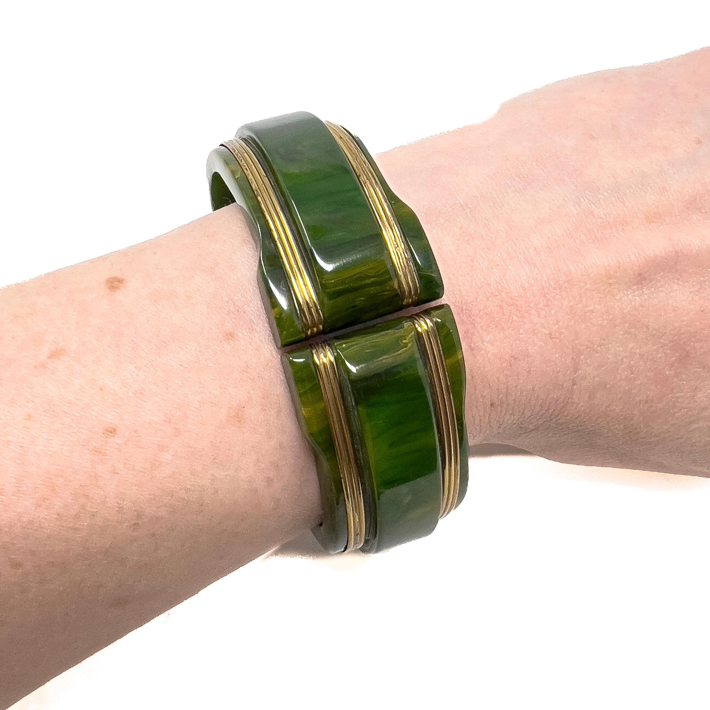 This stylish example of Bakelite jewellery dates from the 1930s. 

Condition Report:
Excellent

The Details...
This hinged cuff is constructed from marbled green Bakelite. It is detailed with 4 gilded metal bands. The internal diameter of this cuff