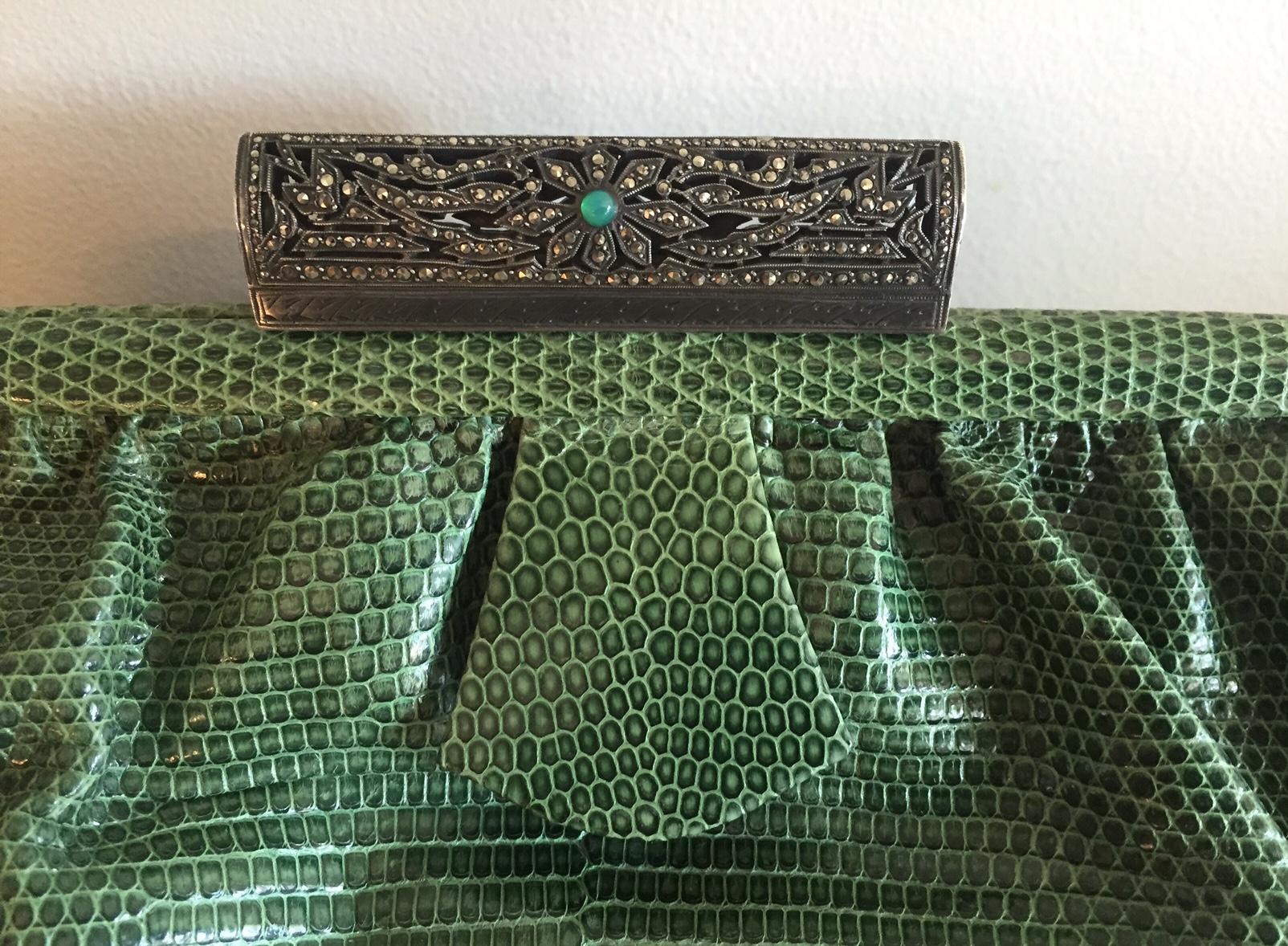 This 1930's Art Deco lizard clutch bag will add a pop of color to any outfit. It has a silver clasp [unmarked so I can't say that it is sterling but that would be my guess] studded with marcasite and a chrysoprase cabochon at the center. This is