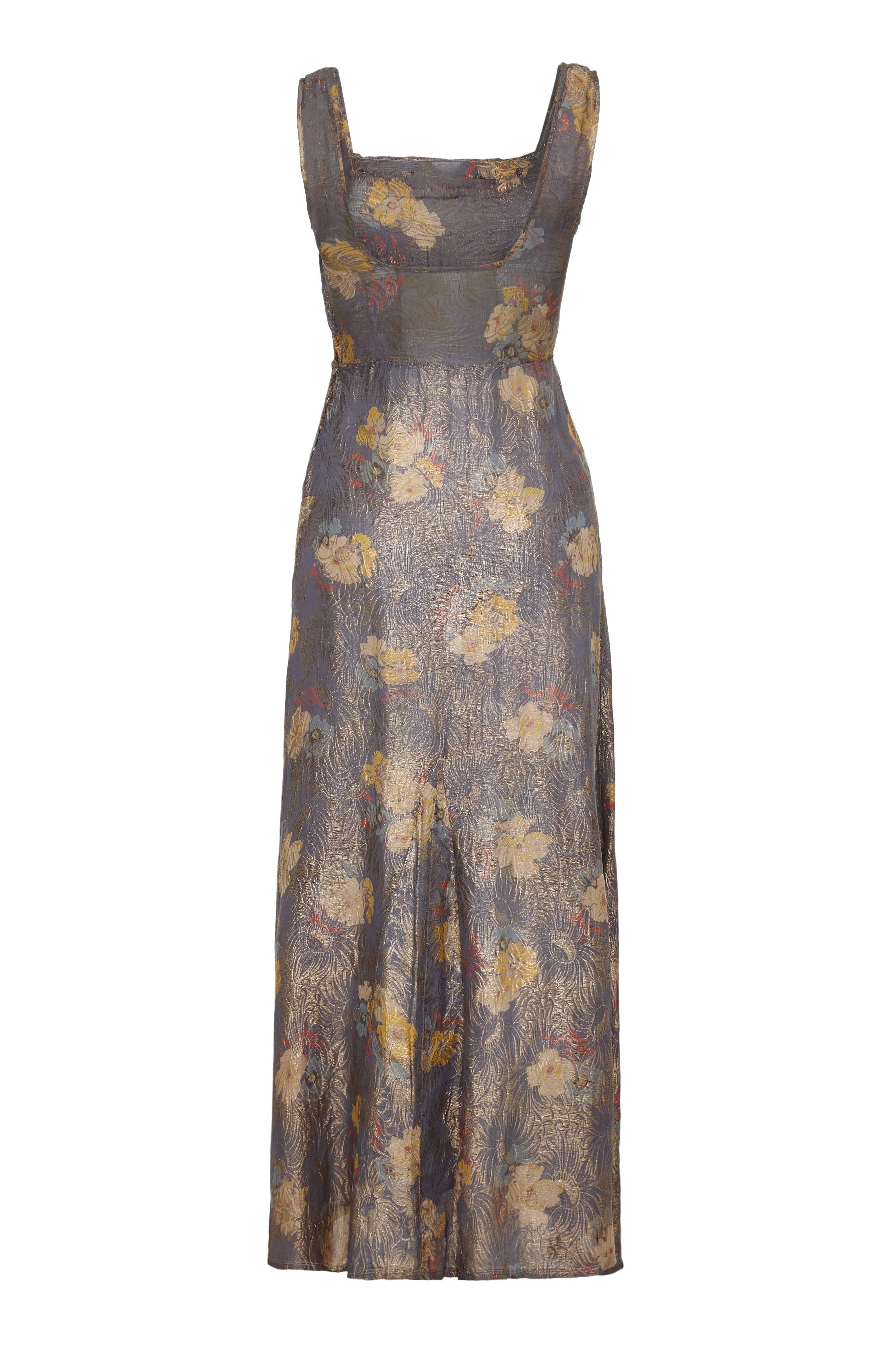 This absolutely enchanting vintage 1930s full length dress in dove grey textured silk with gold lame floral design is in beautiful antique condition. The dress features an empire line bodice and a boat neckline with thick shoulder straps and a