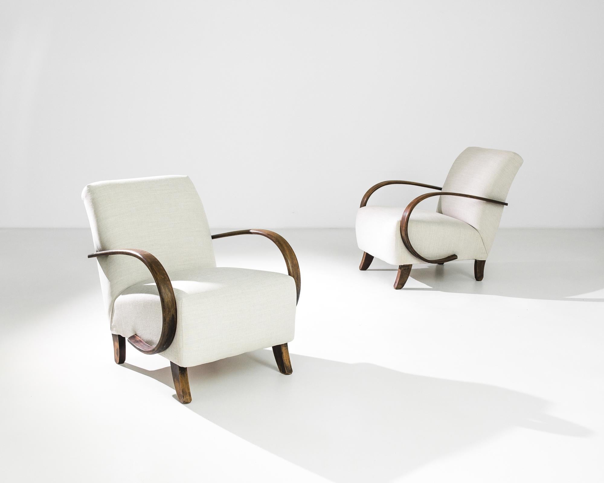 A pair of armchairs by Czech furniture designer J. Halabala. Made in the 1930s, the eye-catching silhouette and comfortable design has an enduring appeal. Influenced by Modern and Art Deco design, a deep upholstered seat upon curved wooden feet is