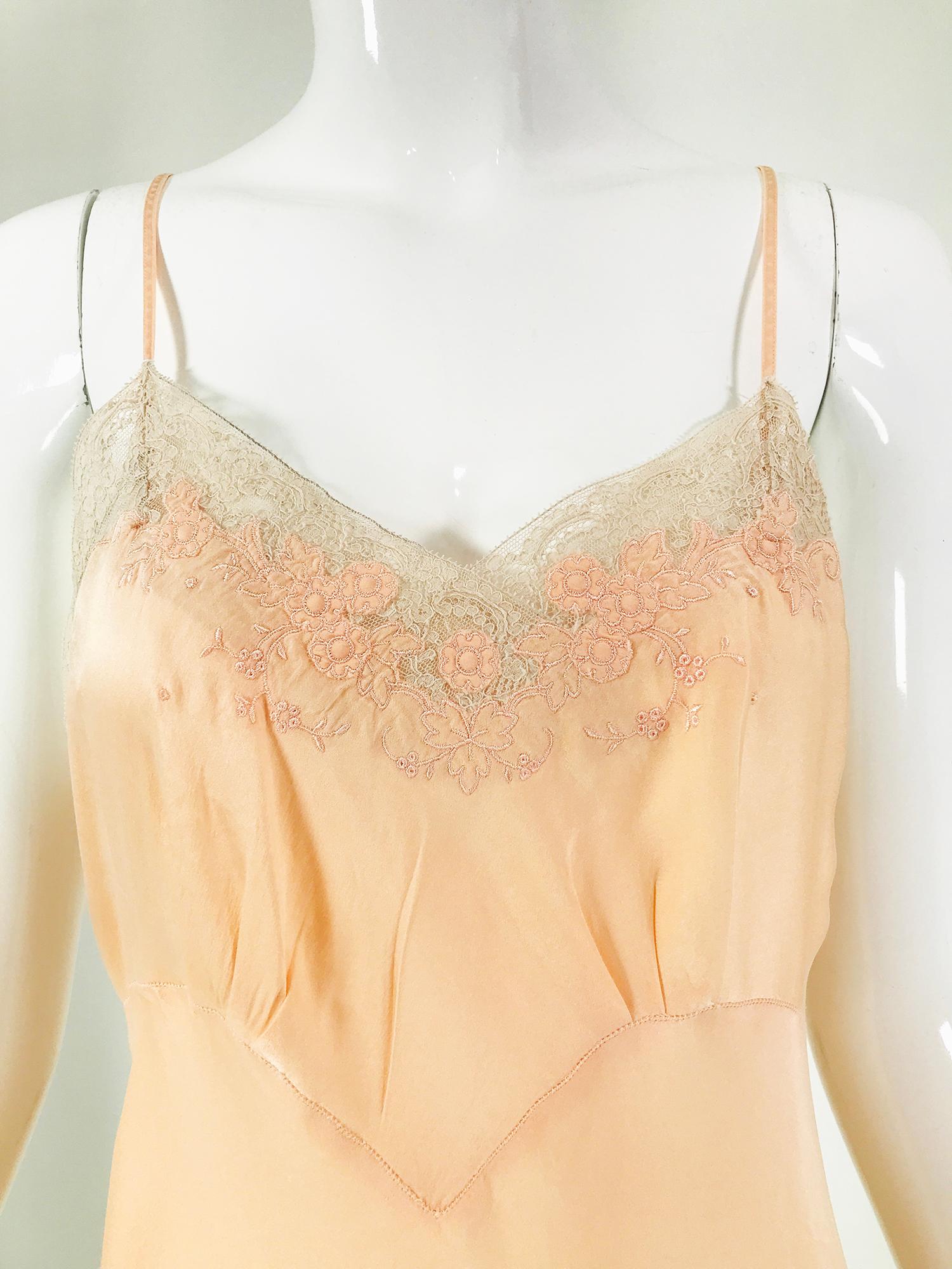 1930s peach silk applique bias cut slip by Hand Look size 36. Cream lace trimmed bodice which is decorated with applique flowers and floral embroidery. Empire bodice with drawn work. The body of the slip is bias cut and flairs at the hem. There are