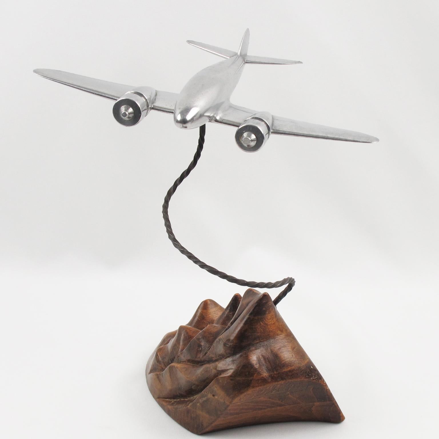 Great looking 1930s wood and aluminum airplane model, mounted on a stylized wooden plinth. This German WWII medium bomber is made of cast aluminum and flying over a carved wood plinth, probably figuring a scene of The Alps mountain. The plane can