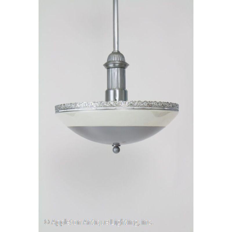 Modernist Pendant. Iridescent glass rim, with steel center to create indirect lighting. Industrial with some ornamentation.

Material: Steel,Glass
Style: Art Deco,Modern
Place of Origin: United States
Period Made: Mid 20th Century
Dimensions: 16 ×