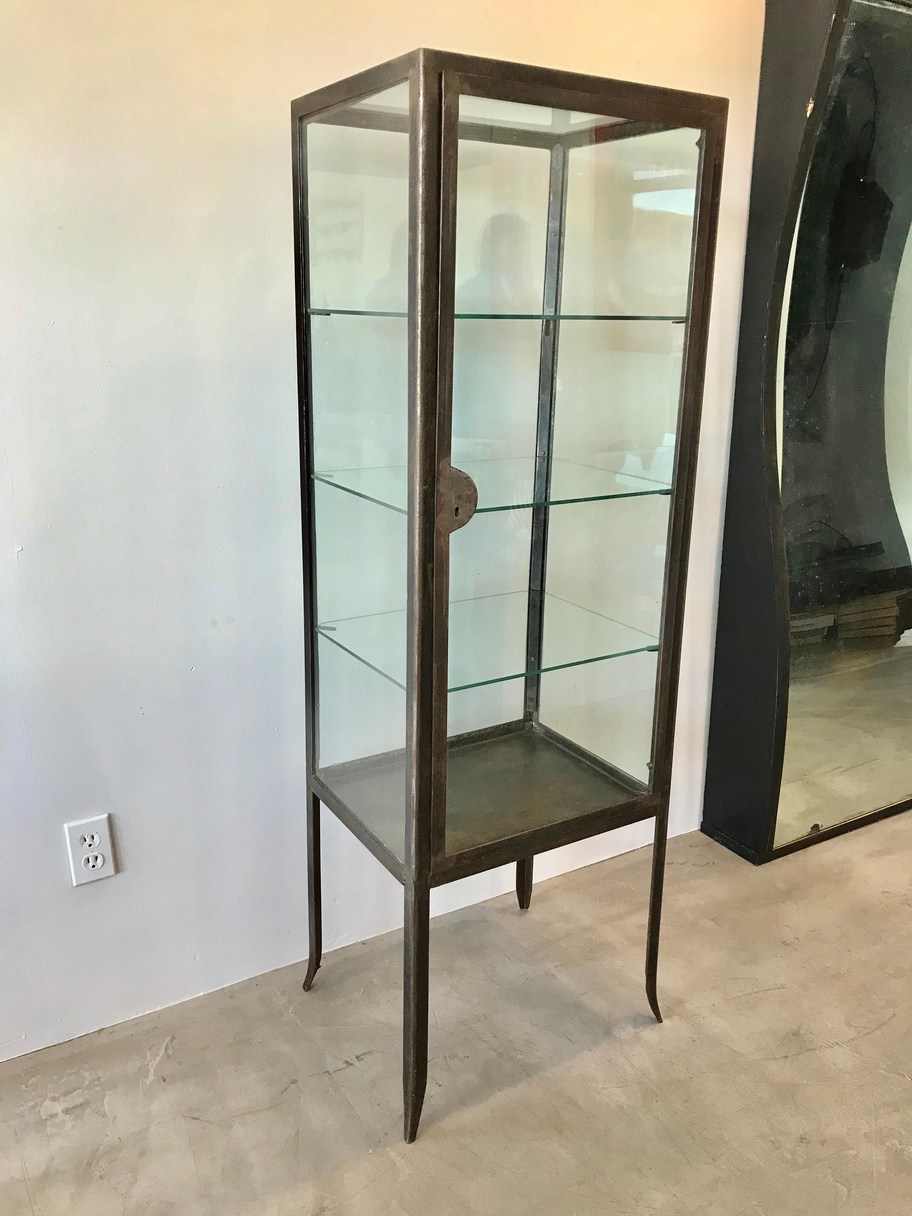 Slender Art Deco vitrine made in the 1930s from Argentina. Rectangular frame sitting atop tapered legs. Original glass frame with rare glass top. New tempered glass shelves with notched corners. Working lock with skeleton key. Fantastic display