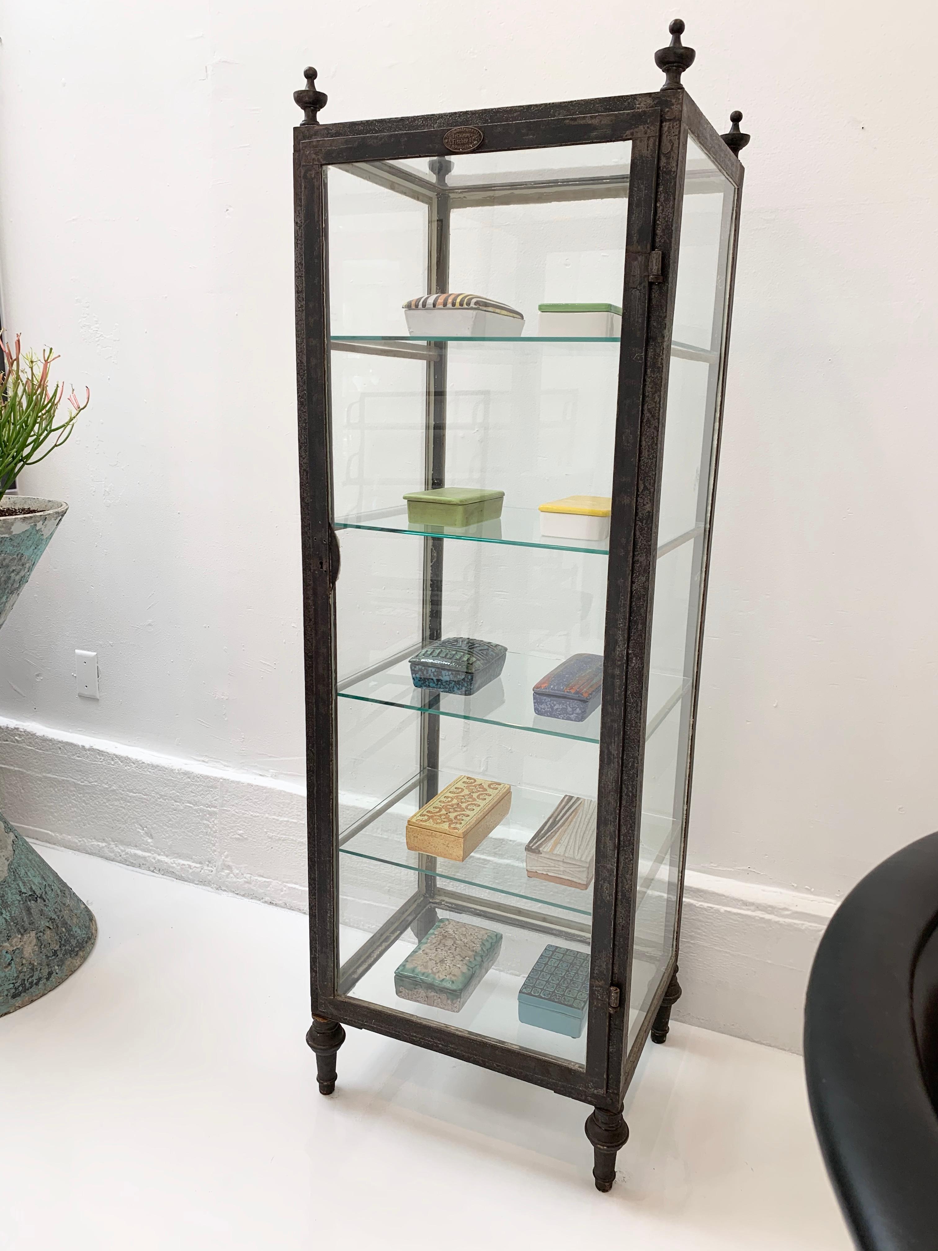 Slender Art Deco vitrine made in the 1930s Brussels, Belgium. Rectangular frame sitting atop post legs with finial top. Original glass frame with rare glass top. Four new glass shelves. Original working lock with skeleton key. Fantastic display