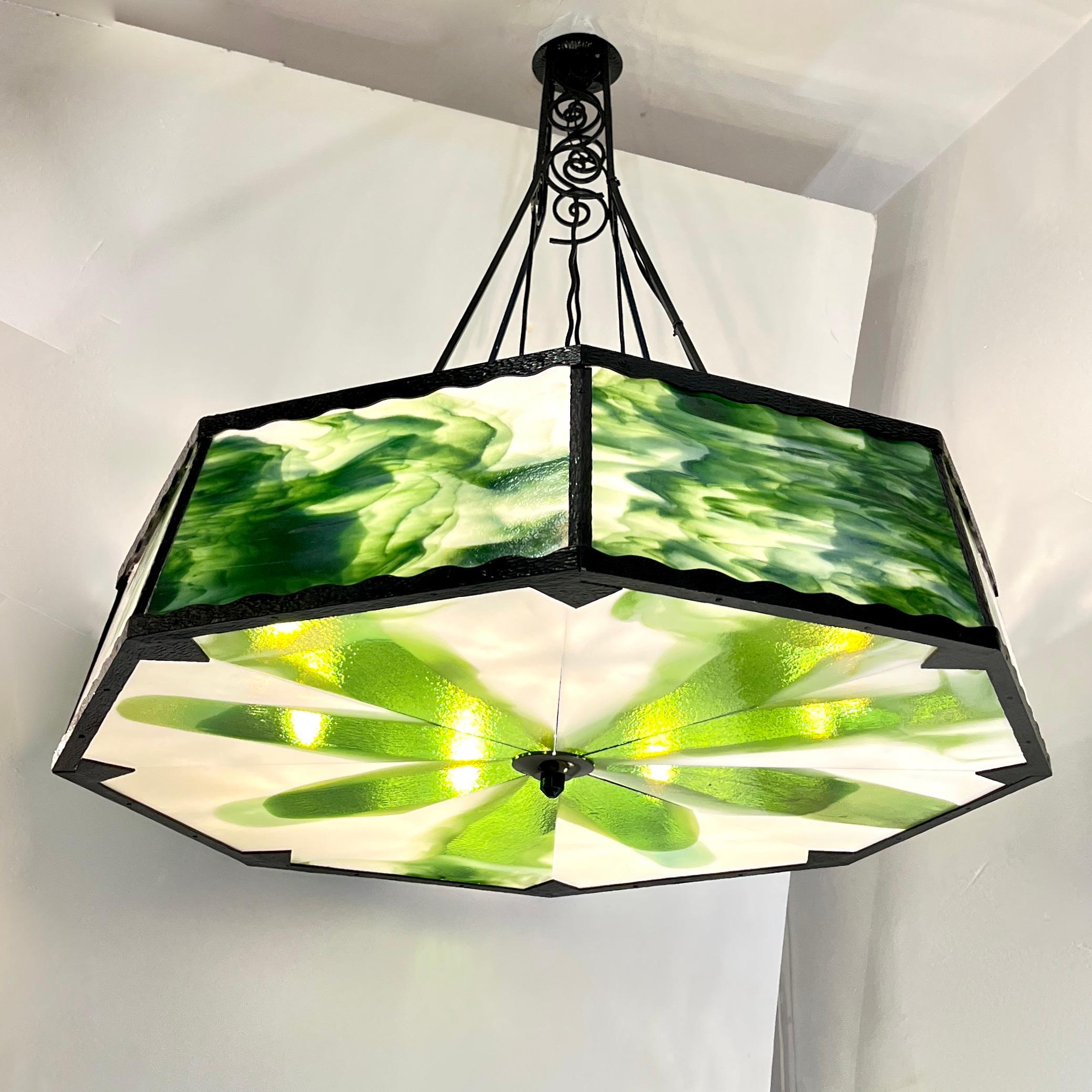 Entirely handmade, one-of-a-kind chandelier from the Italian late Art Deco period, featuring an octagonal, black lacquer hammered wrought iron frame of exceptional craftsmanship, adorned with scalloped edges and intricate, hand-forged scrollwork on