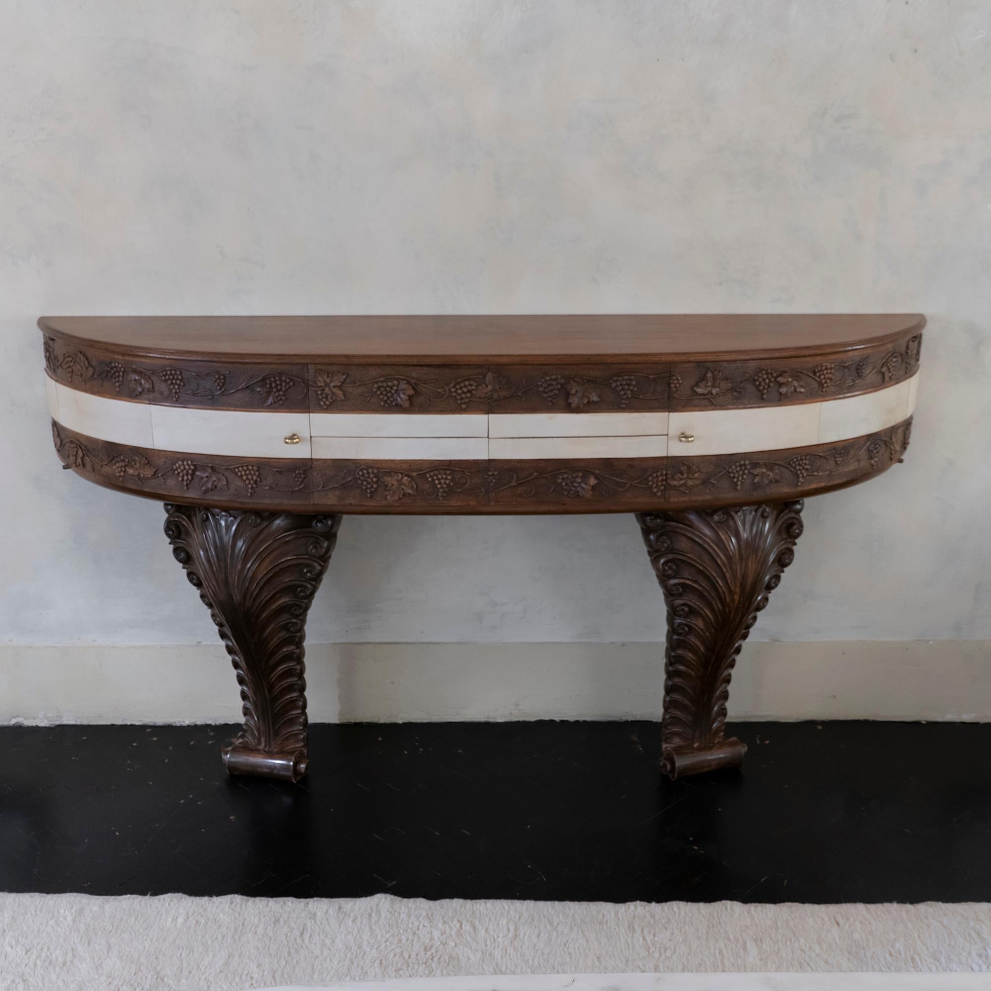 Mid-20th century monumental console in carved wood with decoration of bunches of grapes in the upper part with parchment details, four drawers and two sides sections, inlaid supports,original brass hardware, the console needs to be fixed to the