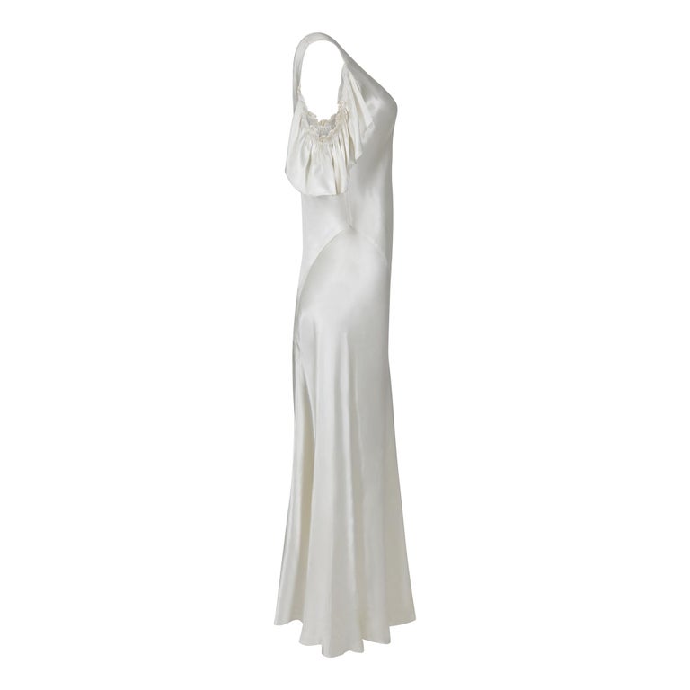 This original 1930s ivory satin wedding dress is a very wearable and has well executed bias cut panels showing considerable pattern and cutting skills. The satin is a bright and shiny ivory colour. The V neck has little bust darts for shaping and