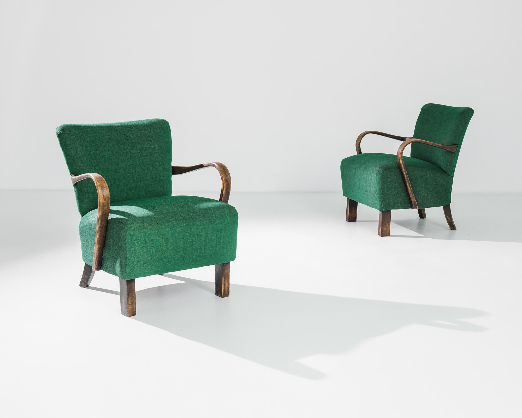 A stylish Mid-Century Modern design and the rich jewel tones of the upholstery gives these pair of 1930s armchairs a unique character. Made by Czech furniture designer J. Halabala, a deep seat upon low legs is framed by fluid bentwood arms and the