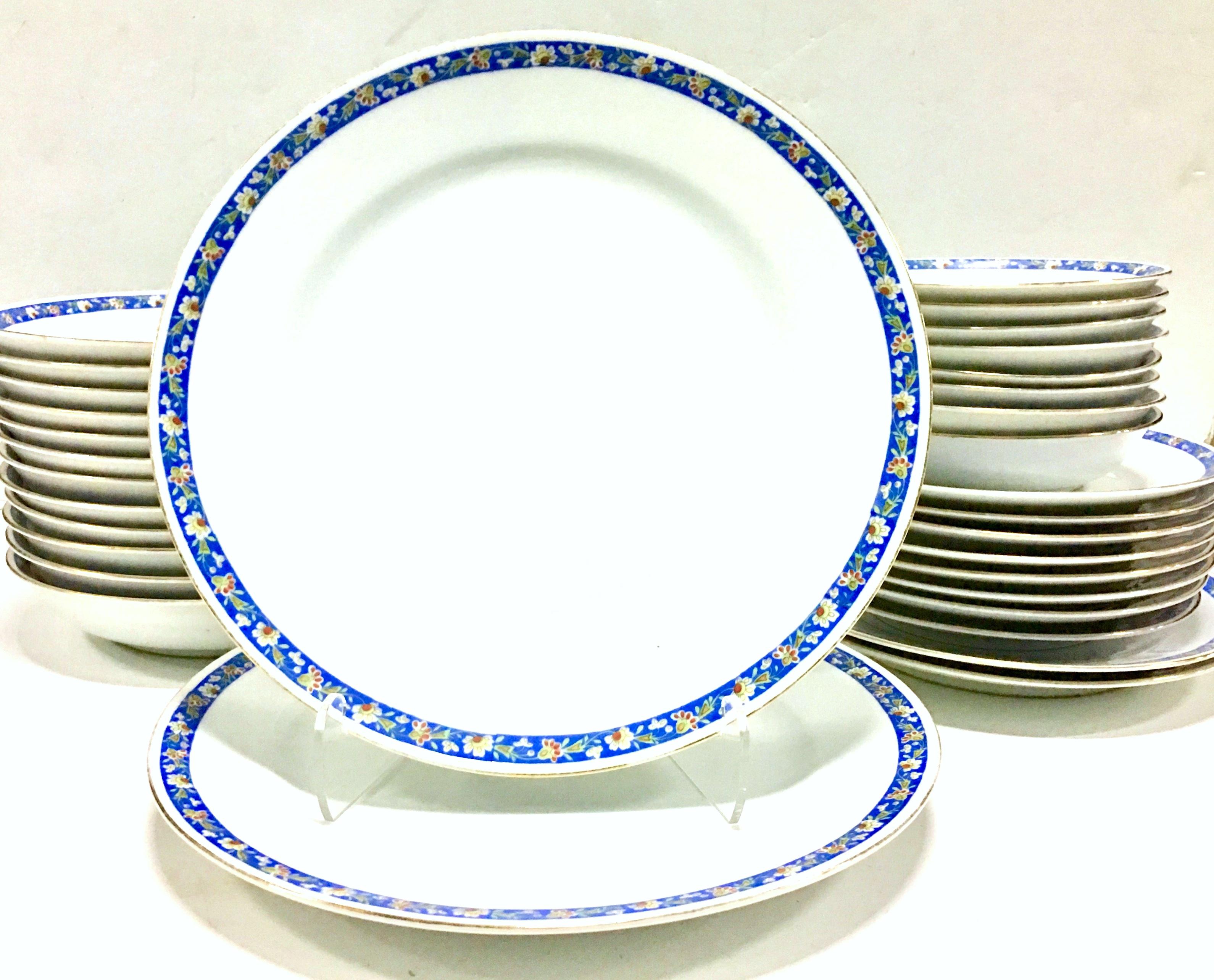 1930s Japanese Art Deco hand painted porcelain dinnerware set of 32 pieces by, Morimura Brothers. Pattern features a bright white ground with a bright blue, green, yellow floral vine motif. There is a 22-karat gold rim edge detail. Each piece is