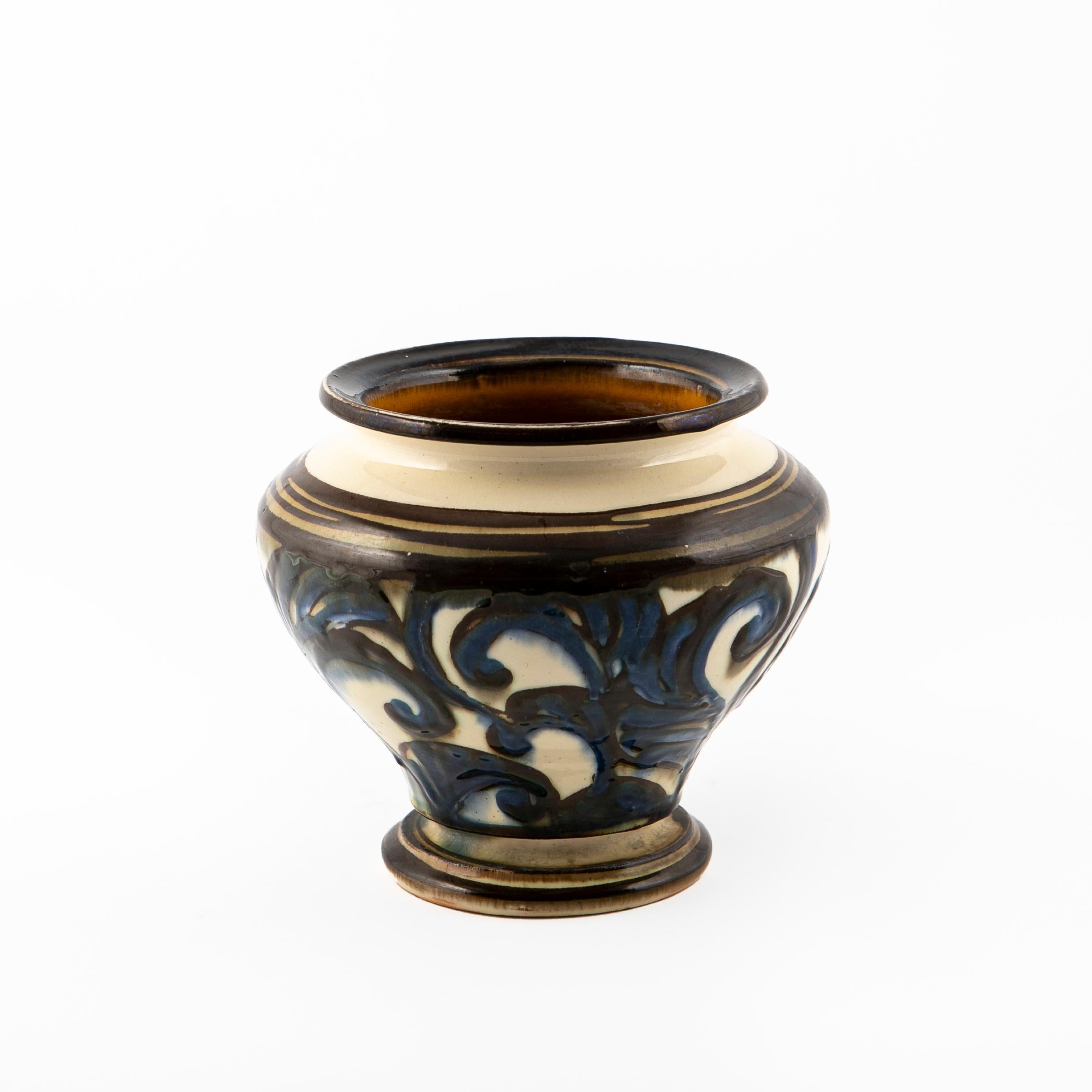 Small glazed ceramic vase with an abstract hand-decorated pattern.
Height: 15 cm.
Blue and brown shades on a bright cream white base. Inside of the vase in yellow ocher glaze.

The underside is signed with the well known logotype HAK.
Denmark 1930's
