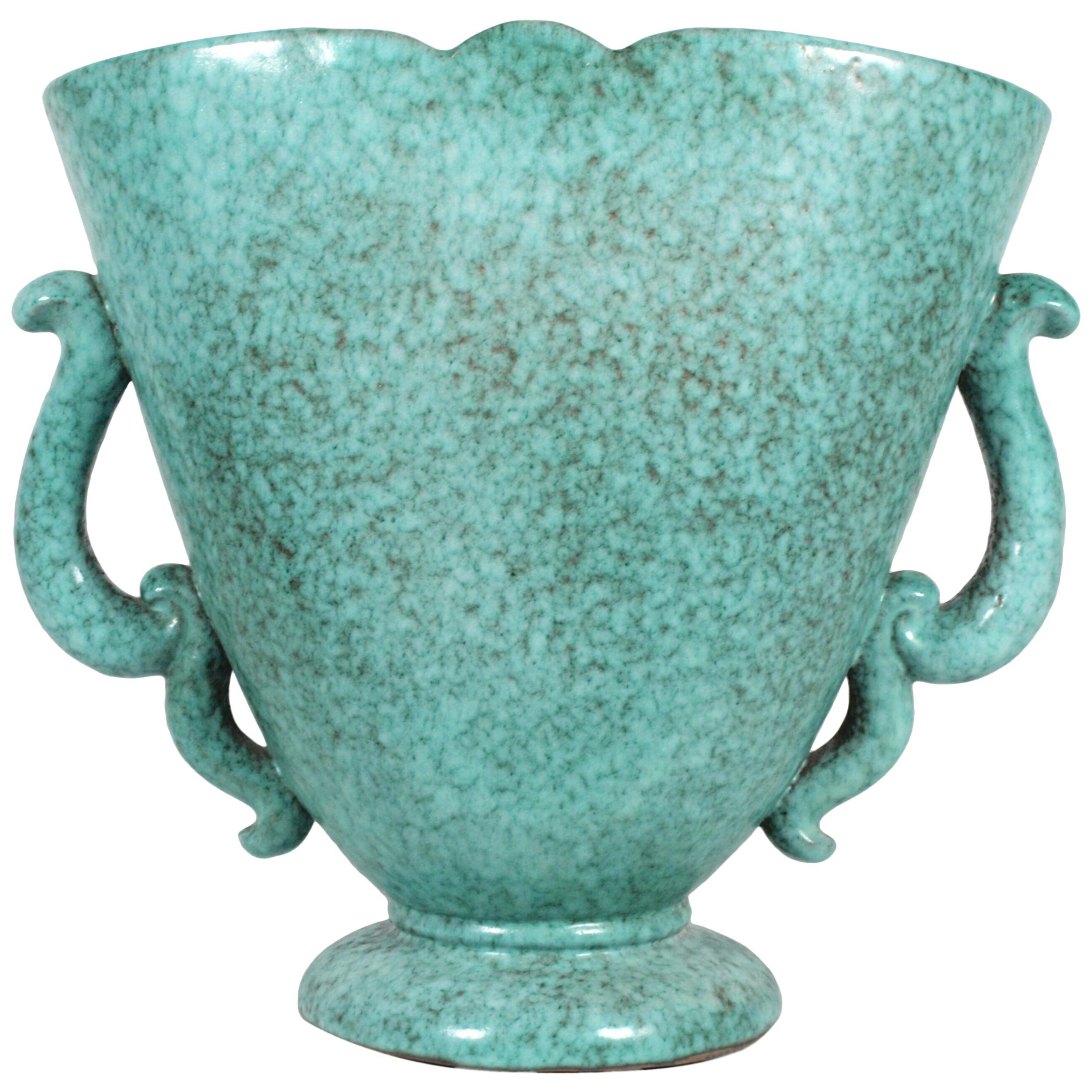 Vase très décoratif des années 1930 de Marcel Noverraz. De forme rythmique avec de somptueuses lignes courbes et des poignées en volute, ce vase plat et évasé repose sur un socle circulaire en céramique et est fini en turquoise tacheté. Signé à la