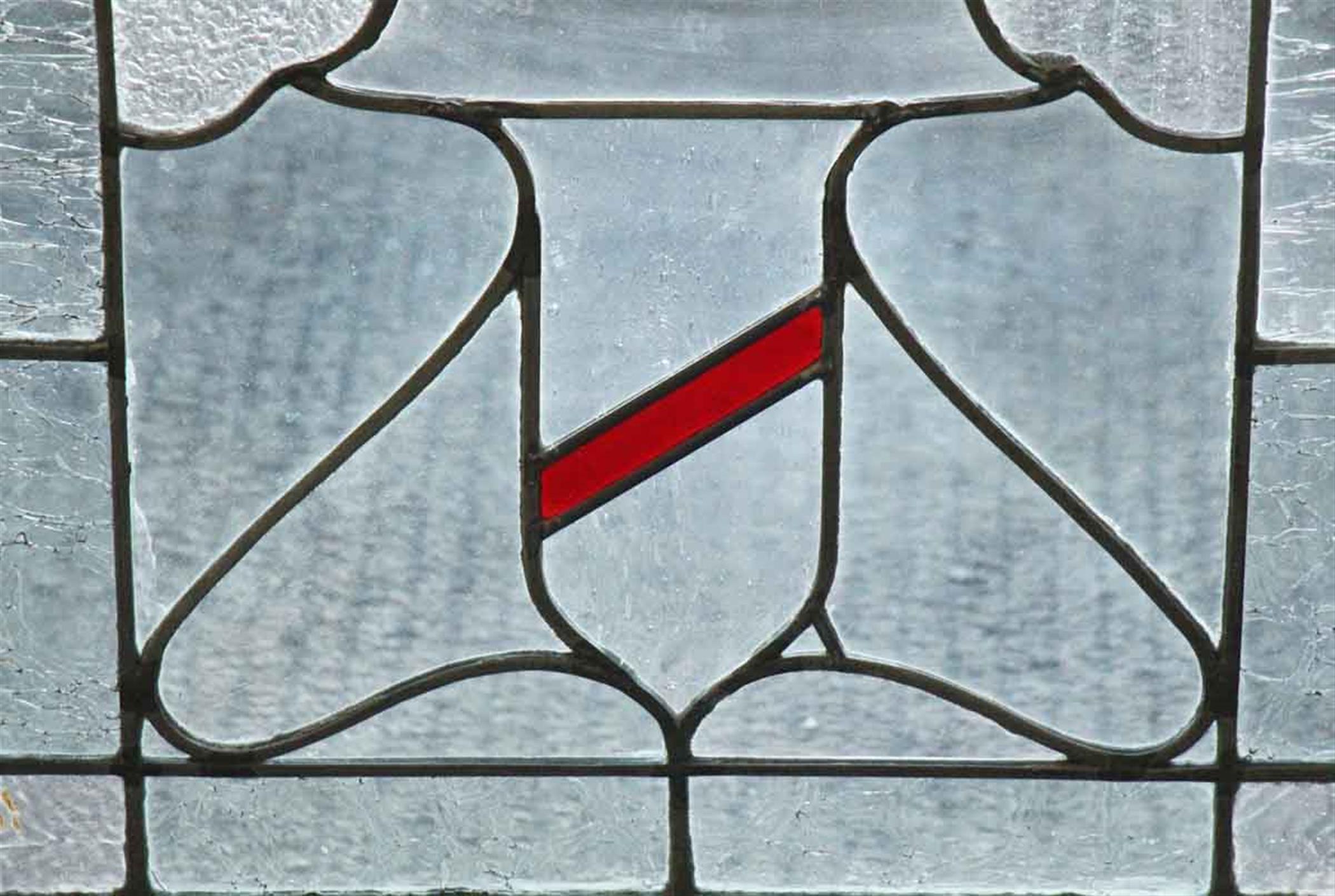 1930s stained glass window with slightly textured glass around the edge and a splash of red stained glass in the center. This can be seen at our 400 Gilligan St location in Scranton, PA.