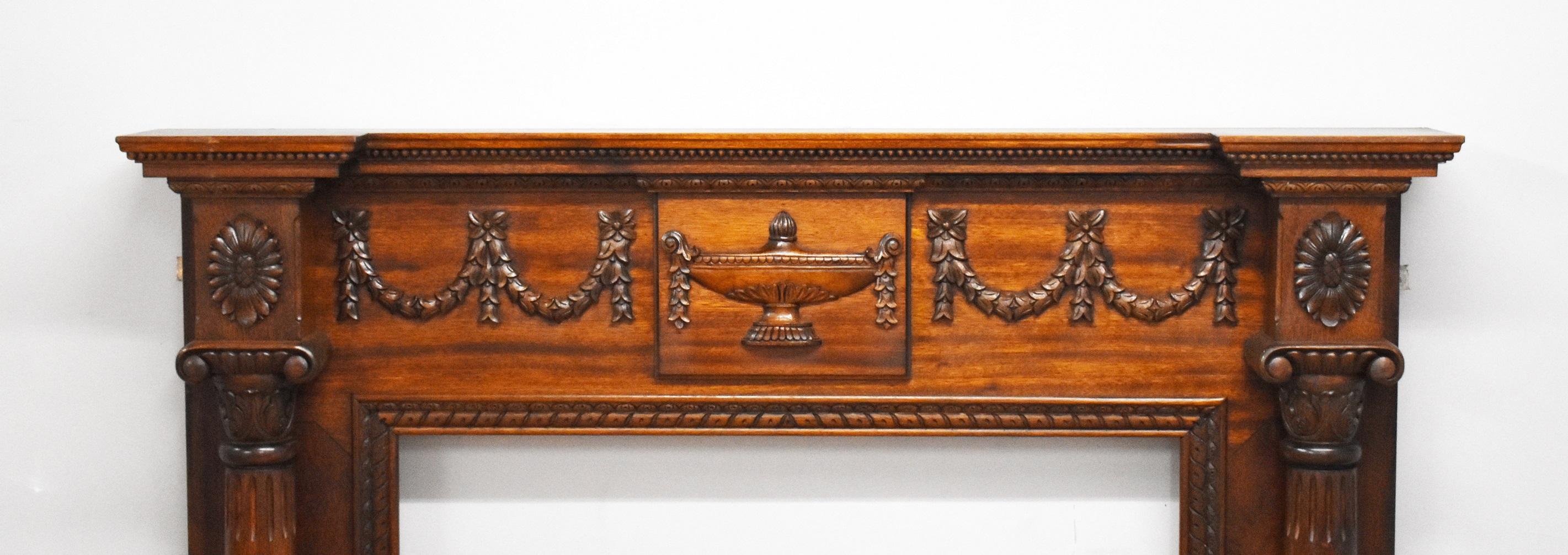 Mahogany fire surround in good condition. To the top are carved swags and tails either side a carved urn to the centre and carved columns to each side.

Inside measurements Width 94cm Height 85cm.