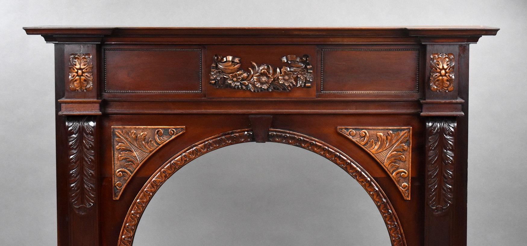 Offered for sale is this 1930s mahogany carved fire surround in good condition with carved flowers to the centre and carved motifs to each column, with a decorative arch.