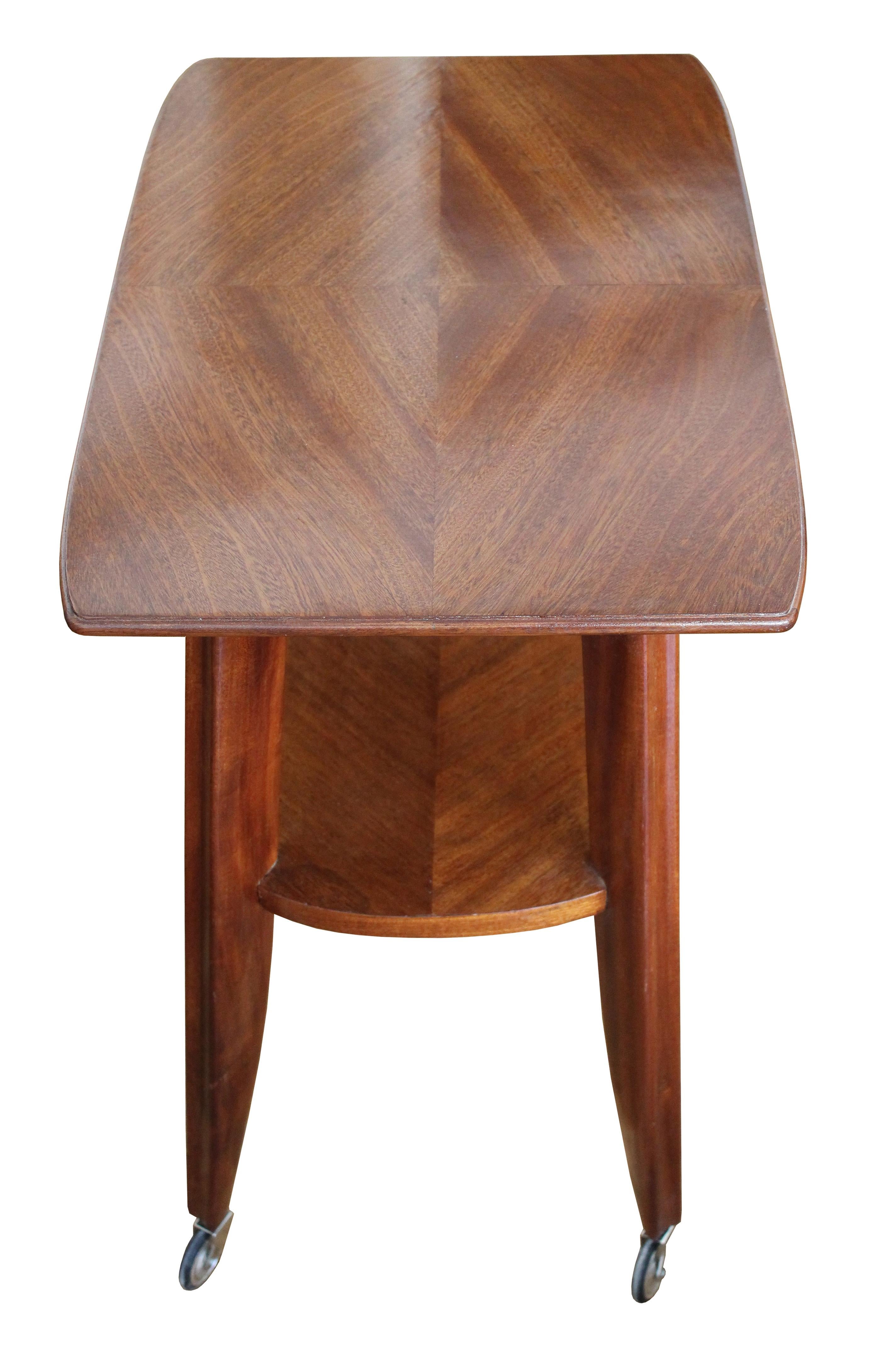 A stunning serving table on caster wheels, made entirely of mahogany wood. 

What makes this piece really stand out is the elegant gentle curves and the rich texture of the mahogany wood on both the top of the piece and the lower shelf. The top