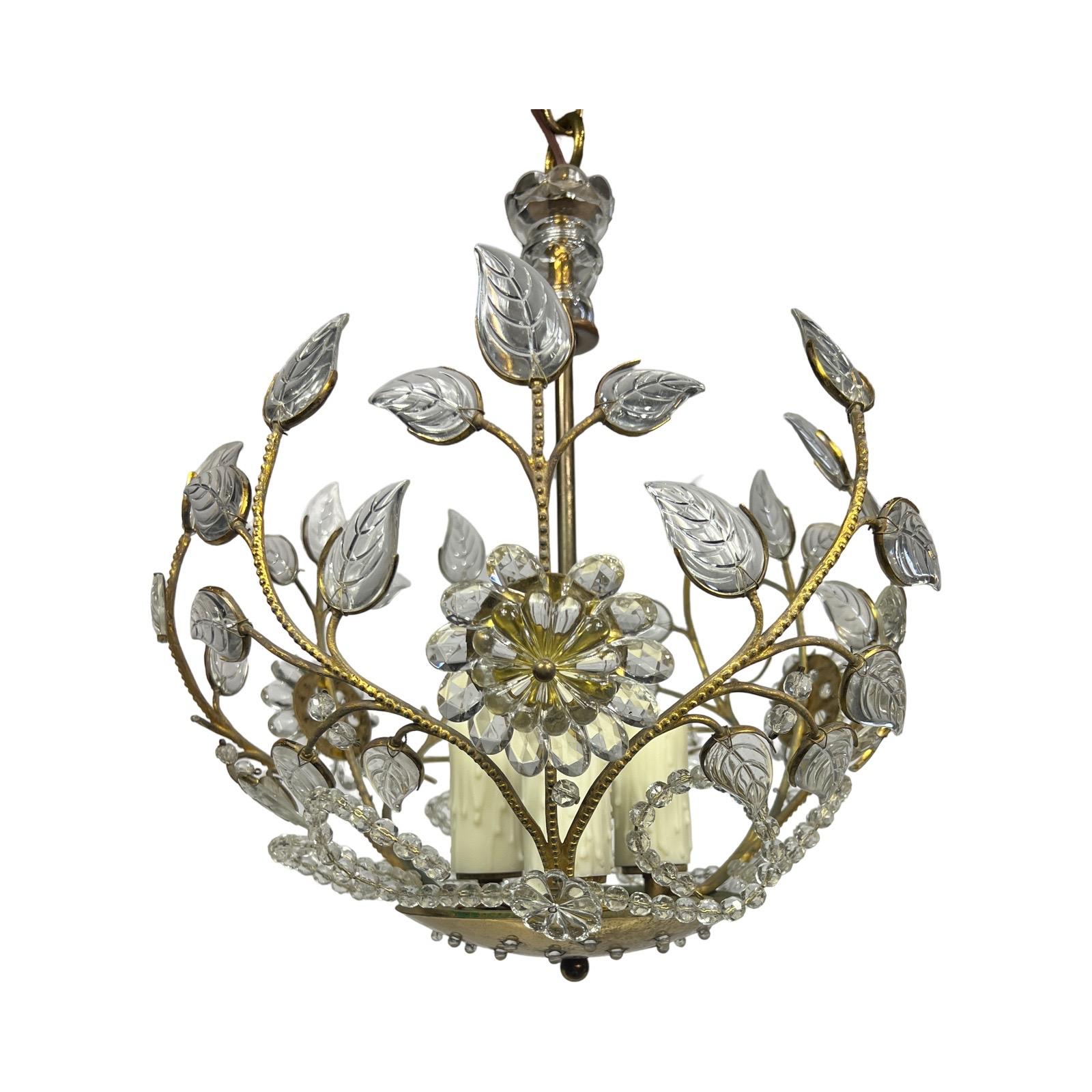 This stunning 1930s chandelier, crafted in the style of Maison Baguès, epitomizes timeless elegance and exquisite craftsmanship. The chandelier features a gilt brass frame adorned with intricate floral and foliate motifs, embodying the delicate