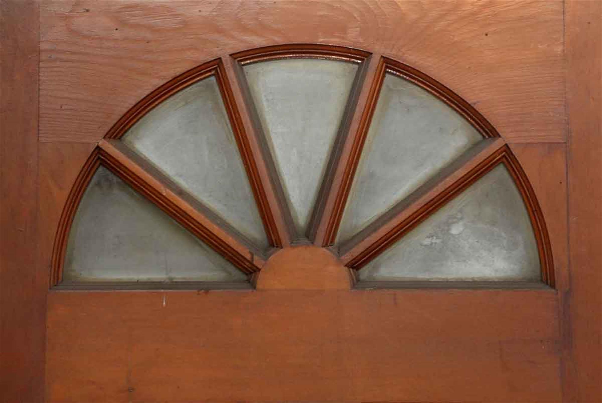 1930s medium wood tone entry door with glass fan shaped panes at the top and four wooden panels. Pleas note the surface mounted hinges indicative of this era. This can be seen at our 302 Bowery location in NoHo in Manhattan.