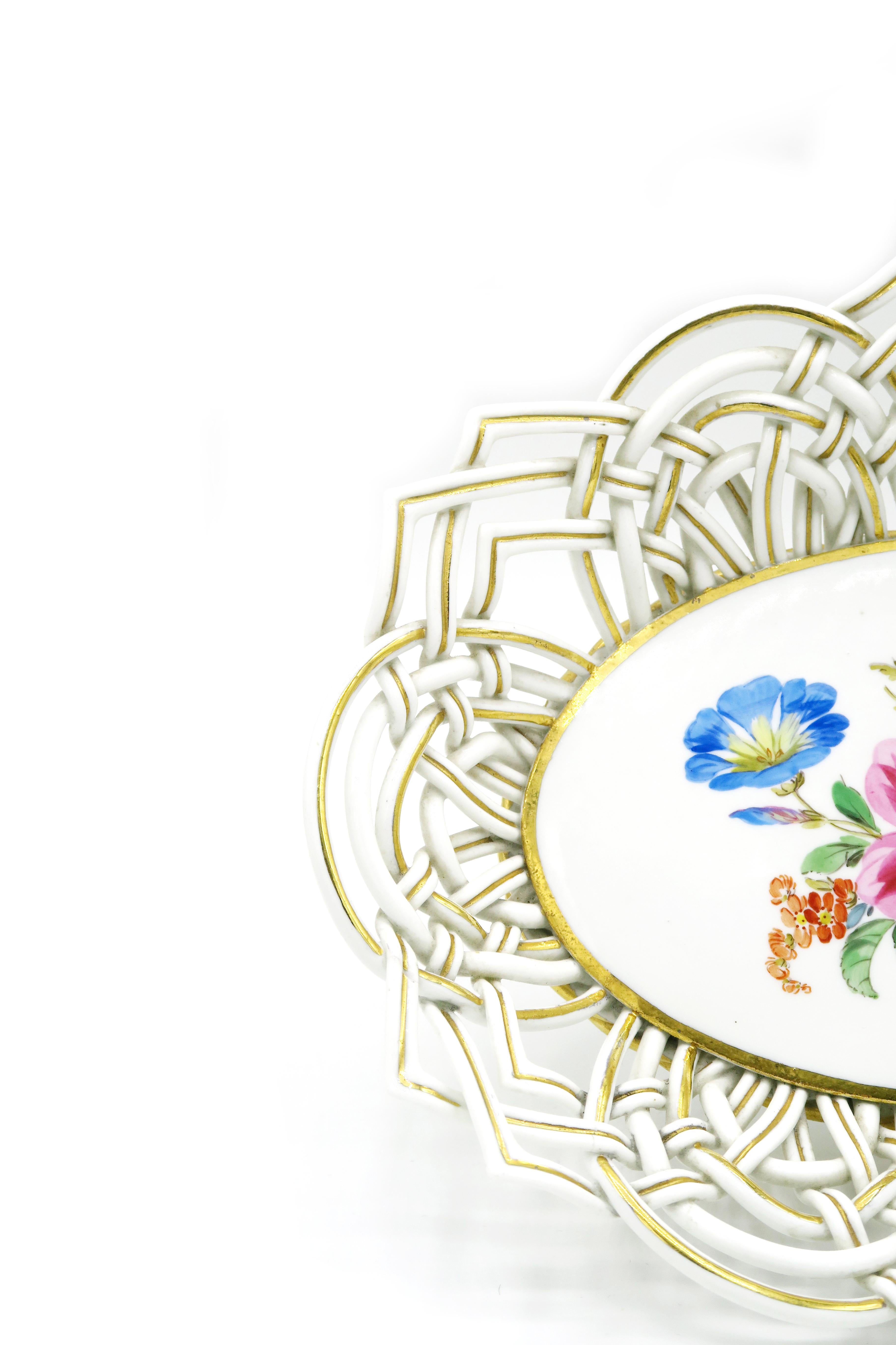Panier à fleurs ovale Meissner des années 1930 avec ornement tressé modelé à la main 
Des fleurs colorées sont représentées sur l'assiette. Forme ovale avec un ornement tressé inhabituel, modelé à la main, partiellement tufté or. Travail sur