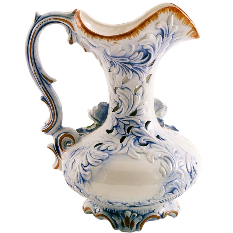 A modern Italian Capodimonte porcelain jug from the midcentury, 1930s, with handle decorated in baroque forms. The pitcher features a colorful garden scene with flowers, twigs and leaves in relief. In excellent condition with no cracks or chaps.