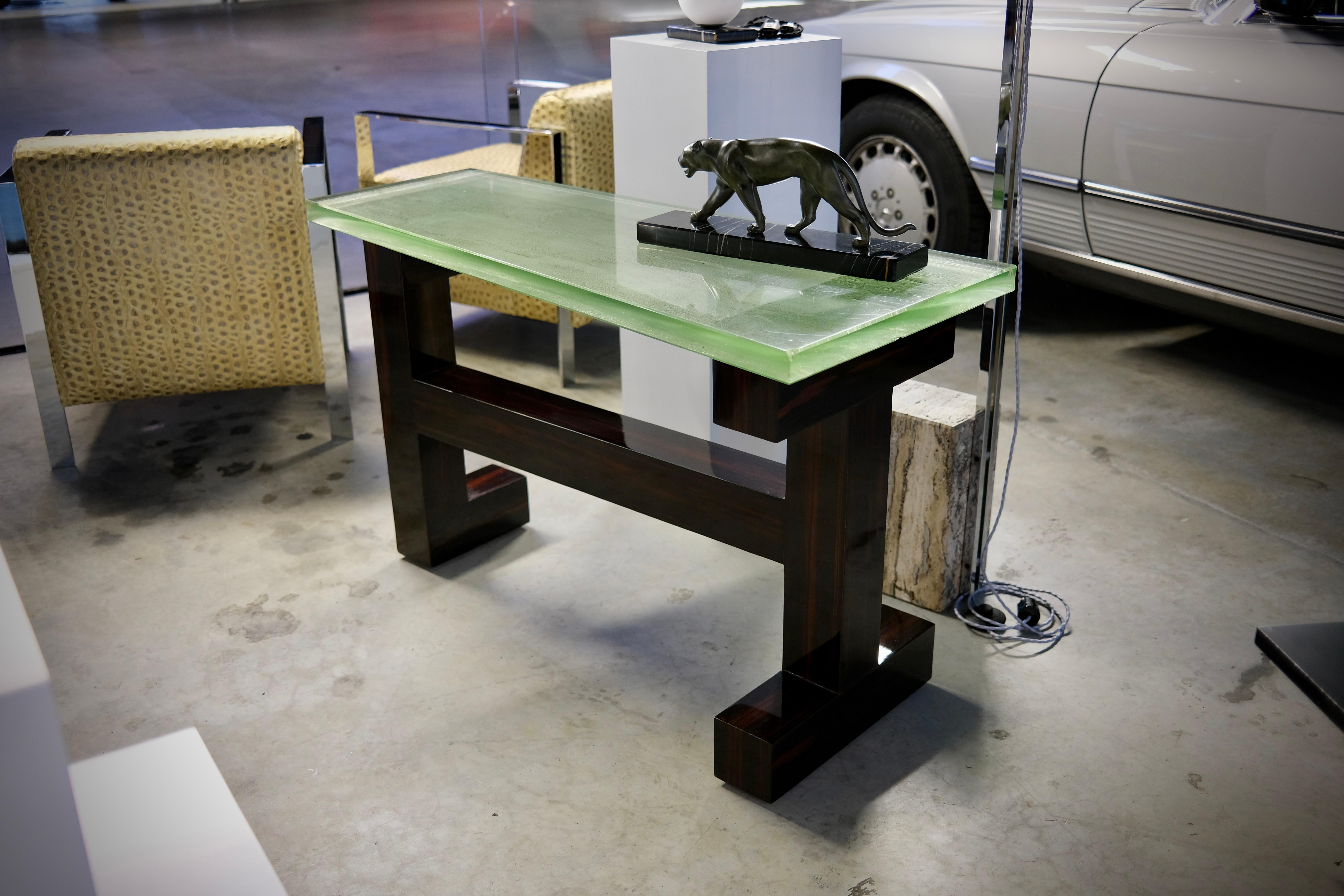 Cette table console peut également servir de petit bureau - elle attire tous les regards.
Forme asymétrique et moderniste en Macassar, laque polie à la main
Plateau en verre épais (coulé dans le sable / de Saint-Gobain), avec des signes d'âge